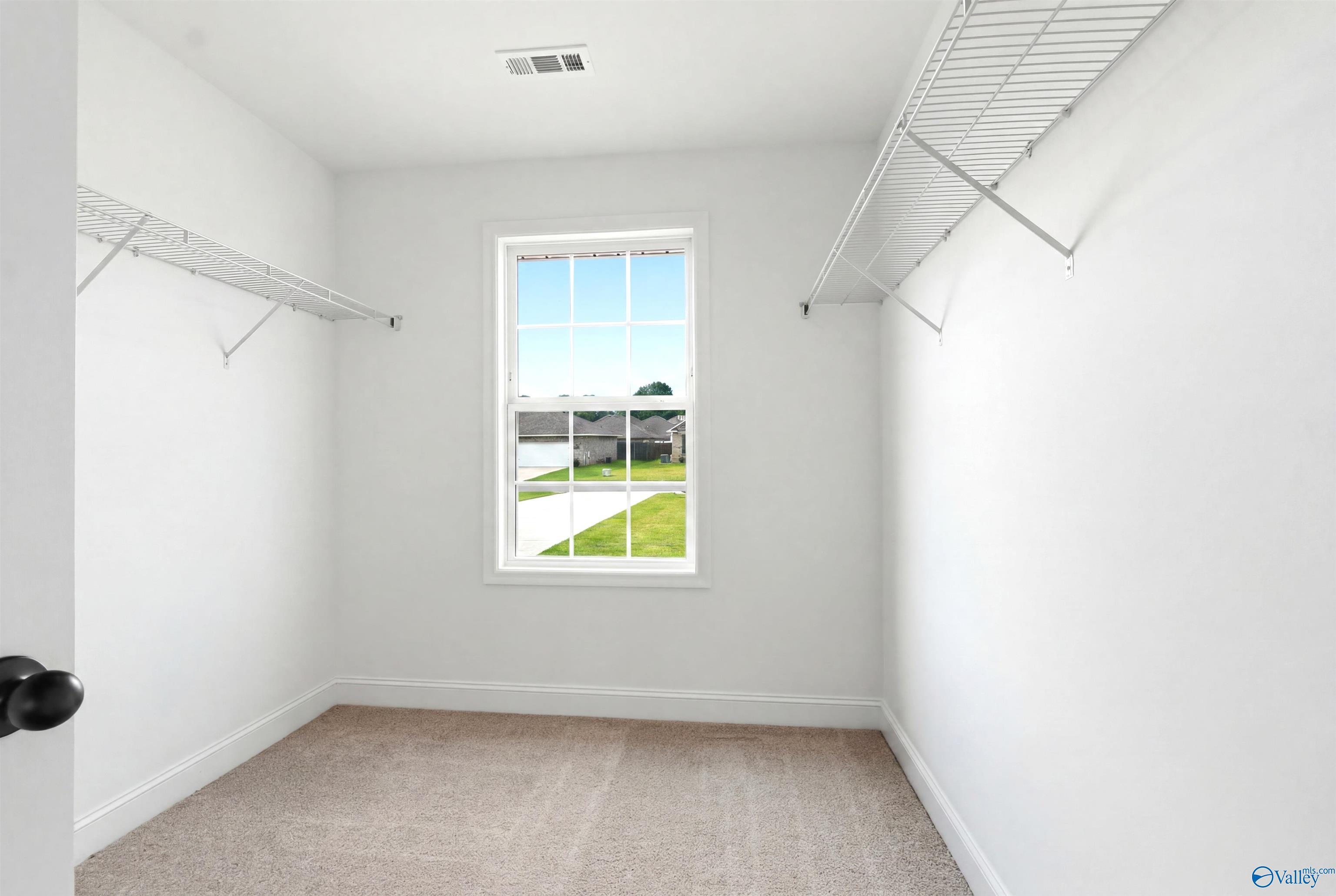 Walk-in closet with wire shelving and window view in The Shelby A floor plan by Davidson Homes in Clearview, Hazel Green, AL.
