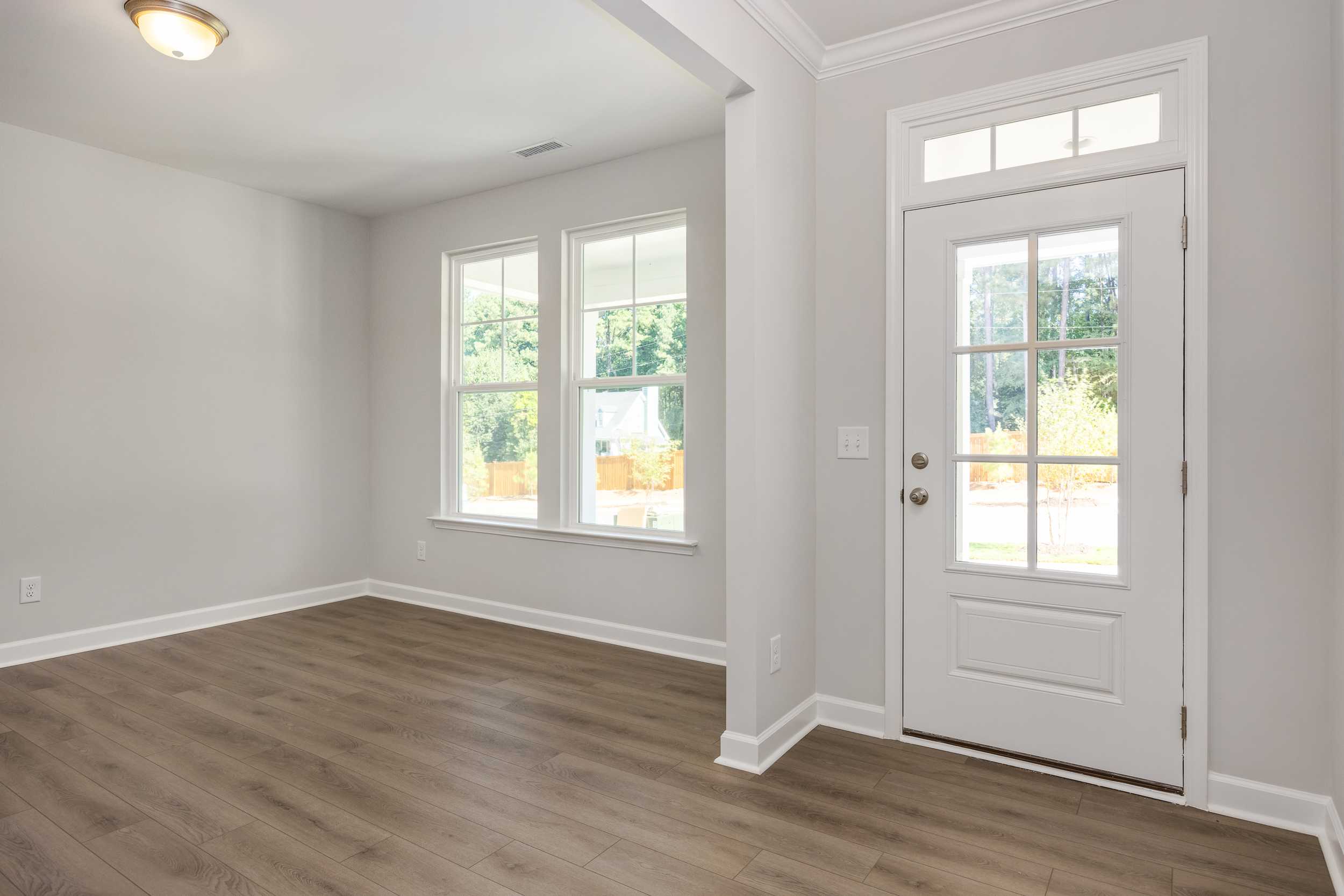 Spacious foyer in The Aspen C by Davidson Homes with hardwood floors, large windows, and white glass-paneled door