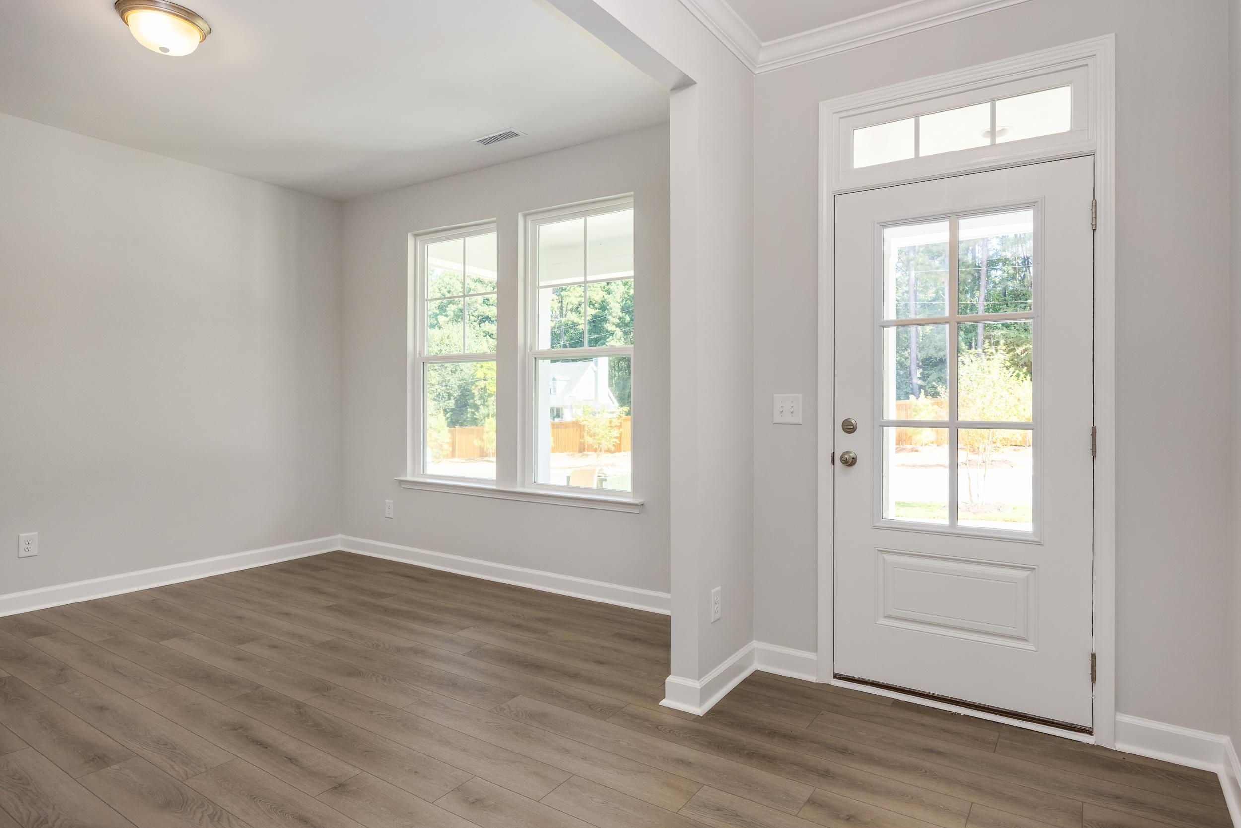 Spacious foyer in The Aspen C by Davidson Homes with hardwood floors, large windows, and white glass-paneled door
