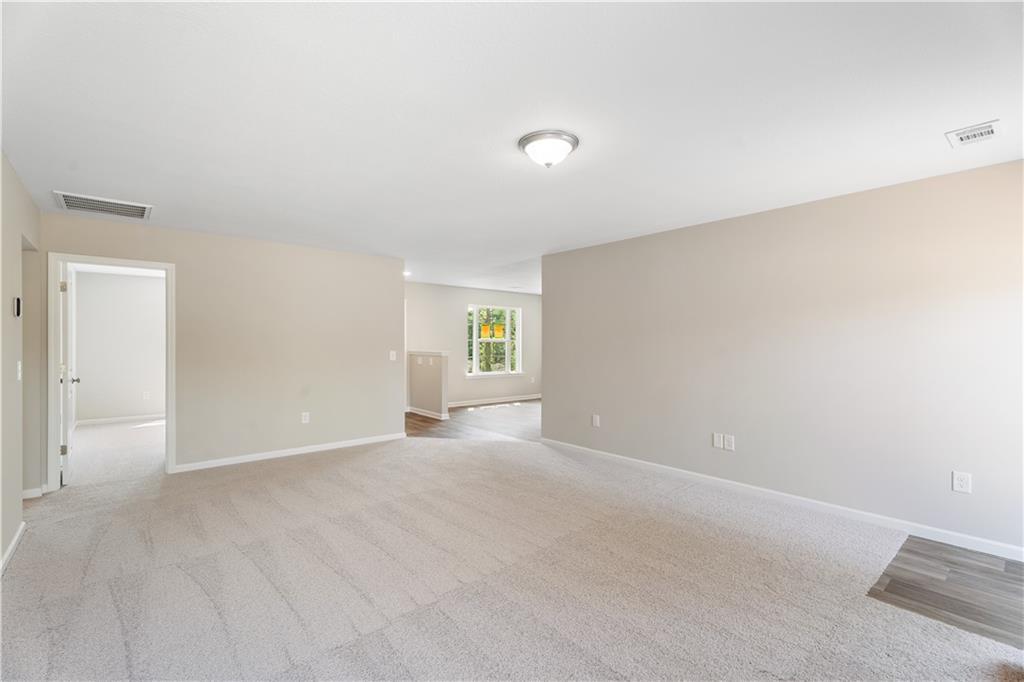 Spacious open living area with beige walls, carpet flooring, and large window in Evermore Homes The Washington, Phenix City, Alabama