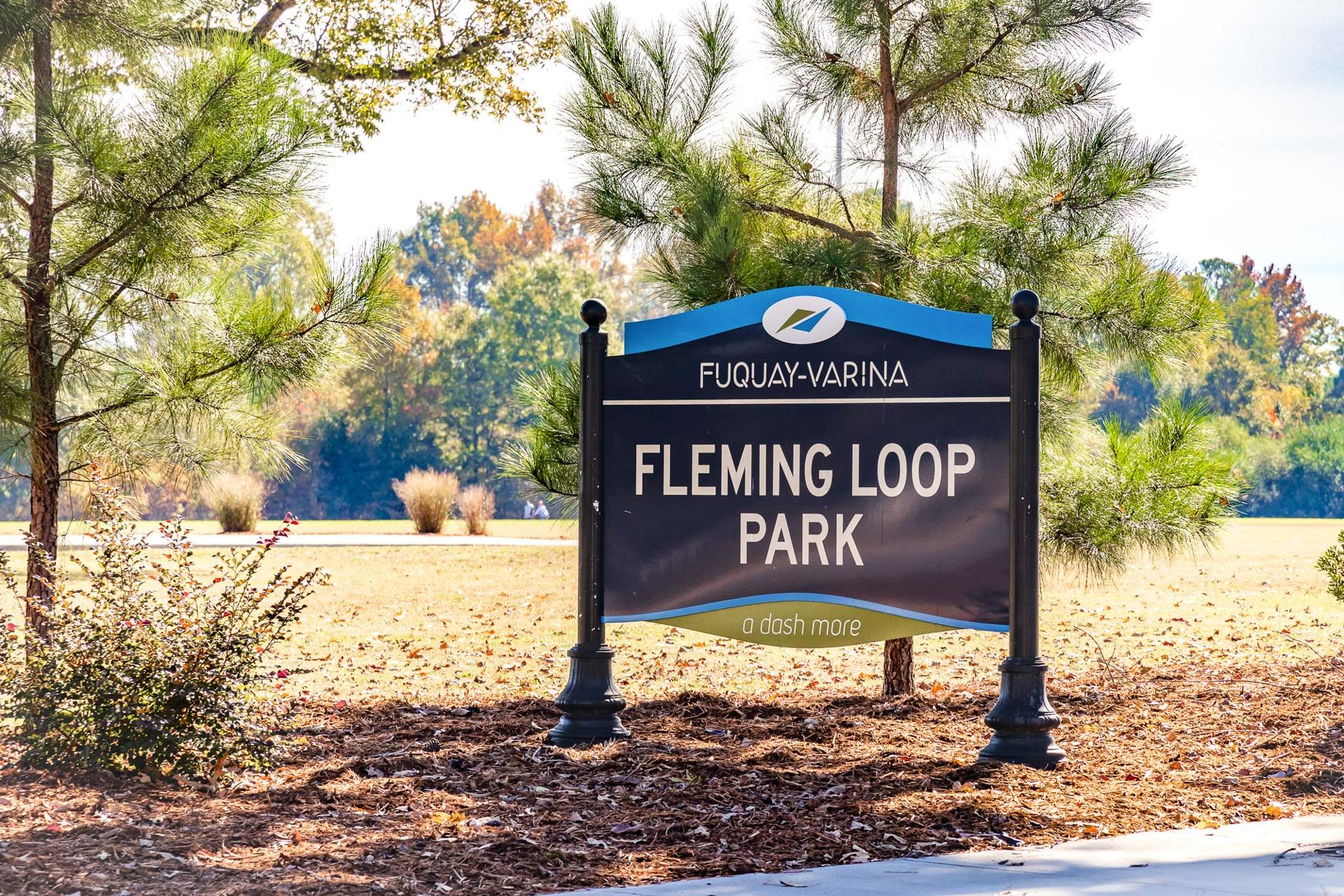 Fleming Loop Park sign in Highland Forest, Fuquay-Varina NC with pine trees, autumn foliage and grassy clearing
