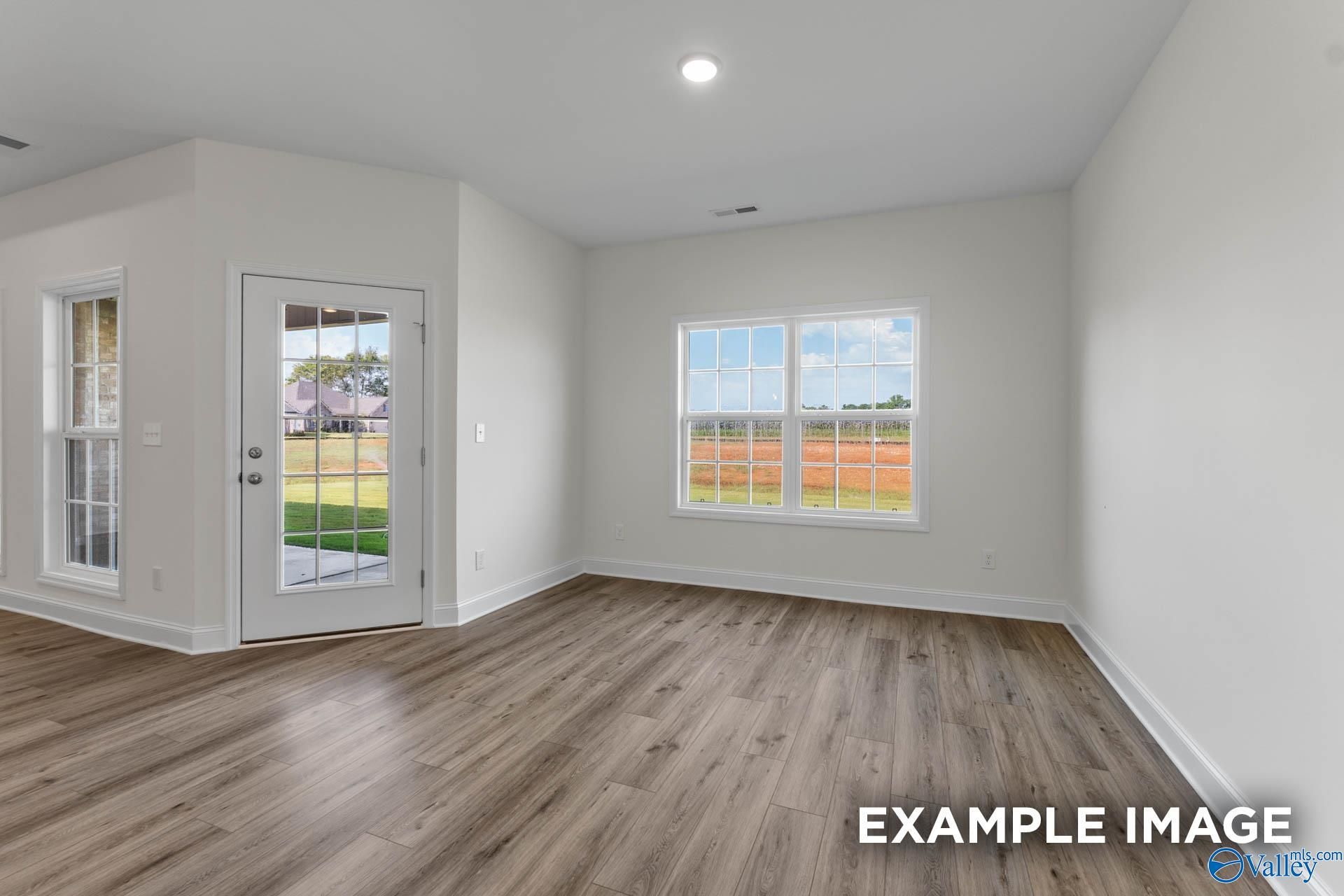 Bright airy room with large windows and exterior door overlooking green lawn and fields in Davidson Homes The Harrison C, Athens Alabama