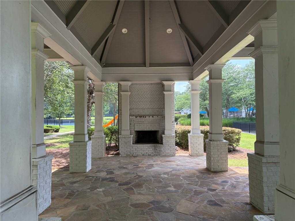 Open pavilion with white brick fireplace, stone floor, and playground view in Riverwood, Dallas, Georgia