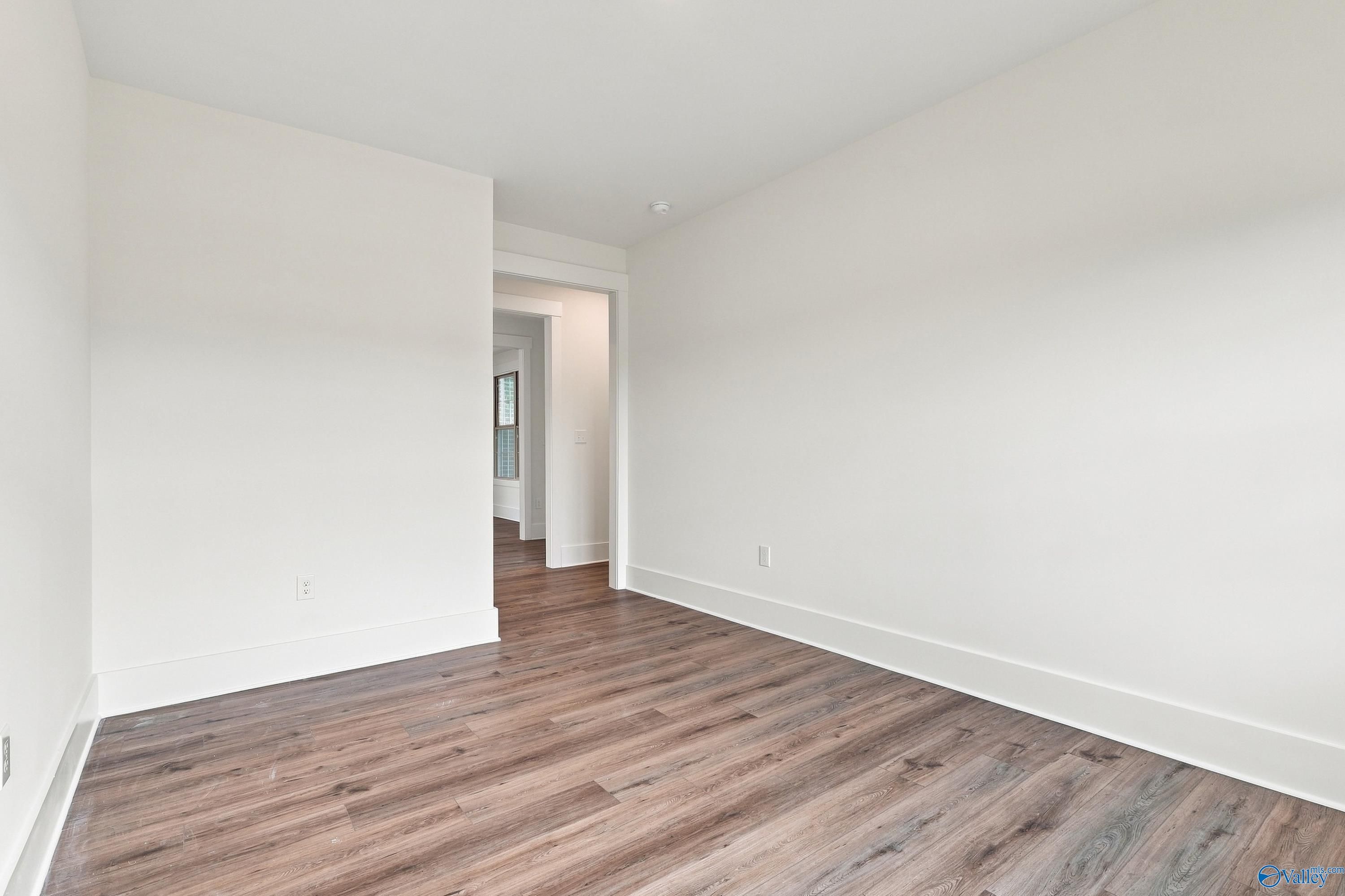 Empty bedroom with wood-look flooring and white walls in Davidson Homes' The Valencia, Riverton Preserve, Huntsville, Alabama