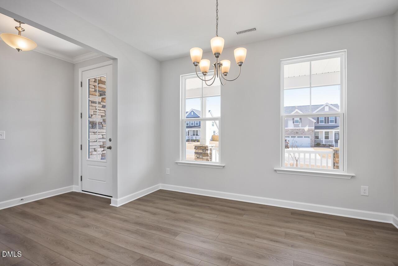 Bright dining room with elegant chandelier, large window viewing neighborhood homes, hardwood floors in The Willow G, Angier, NC