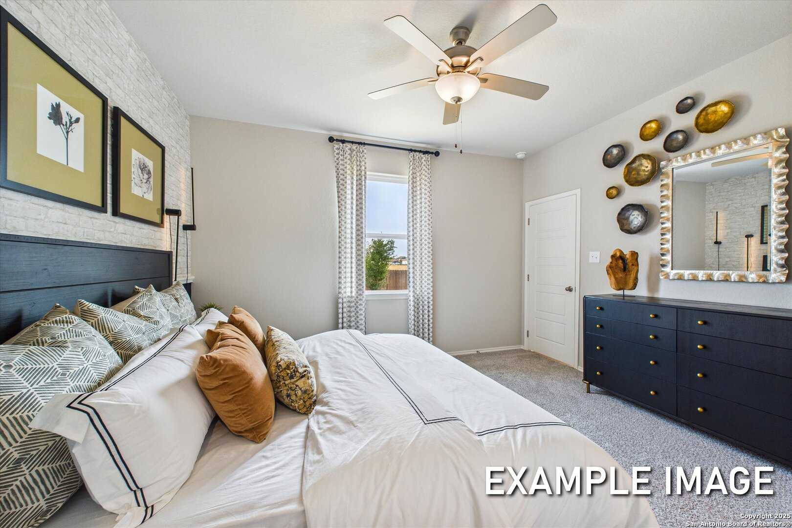 Luxurious master bedroom with king bed, orange pillows, black headboard, ceiling fan in Davidson Homes Sabine C, San Antonio