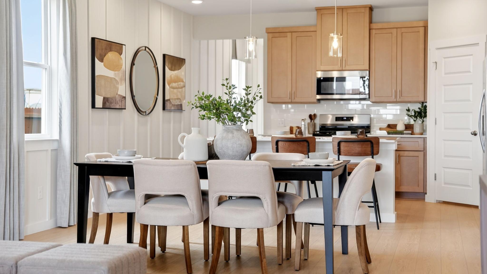 Open-concept dining and kitchen in Heartland Texas Davidson Homes home with light oak cabinets, island stools, and hardwood floors