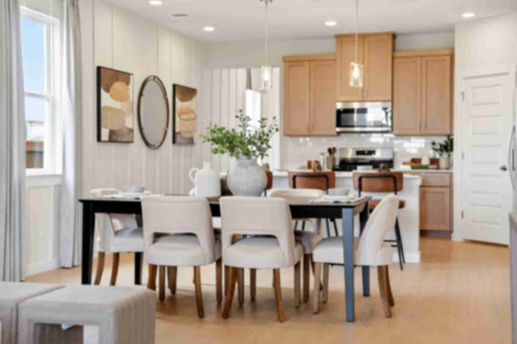 Open-concept dining and kitchen in Heartland Texas Davidson Homes home with light oak cabinets, island stools, and hardwood floors
