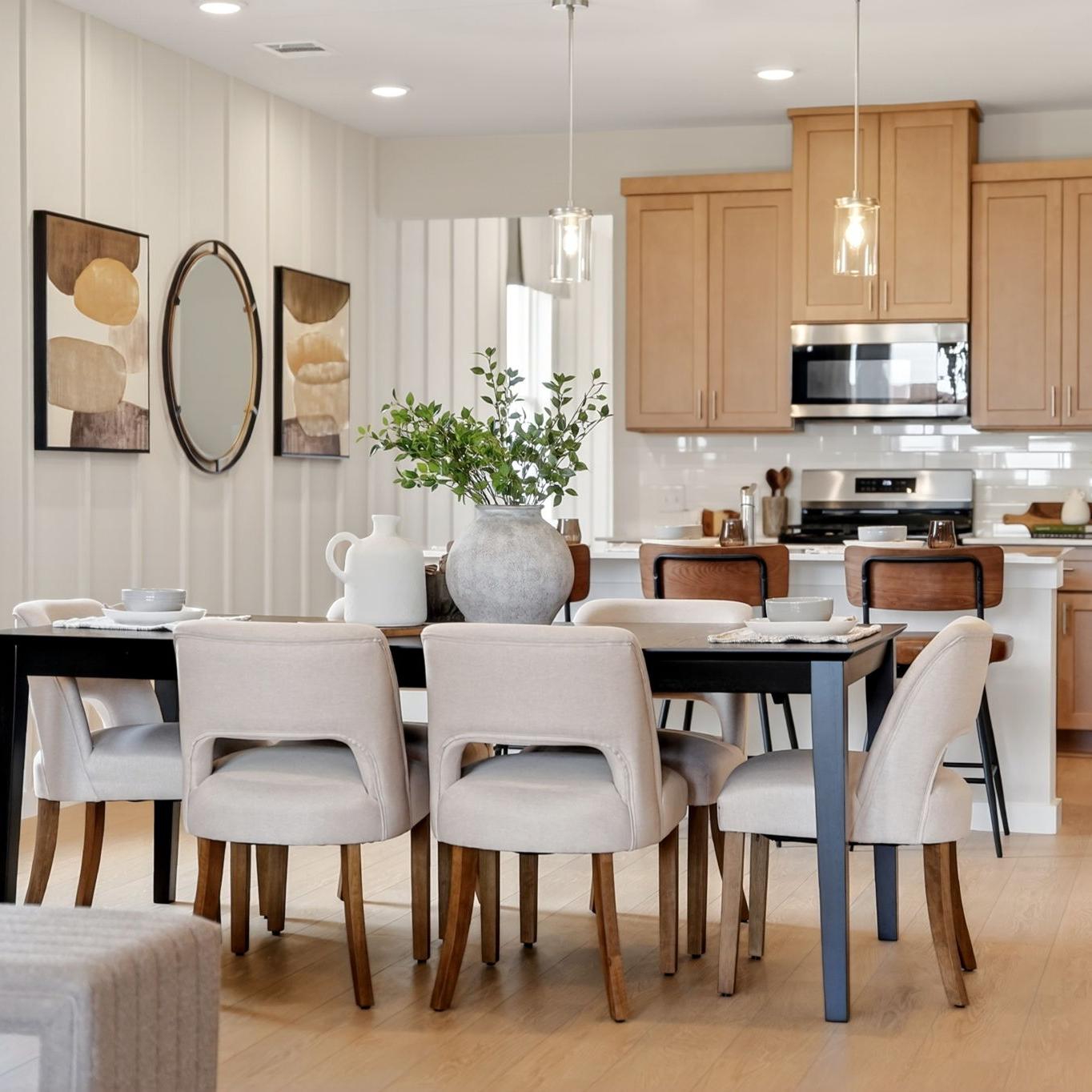 Open-concept dining and kitchen in Heartland Texas Davidson Homes home with light oak cabinets, island stools, and hardwood floors