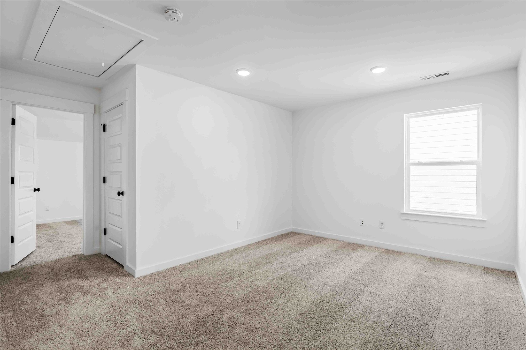Bright, carpeted secondary bedroom with white walls in The Ash O floor plan by Davidson Homes in Heartland, Texas.