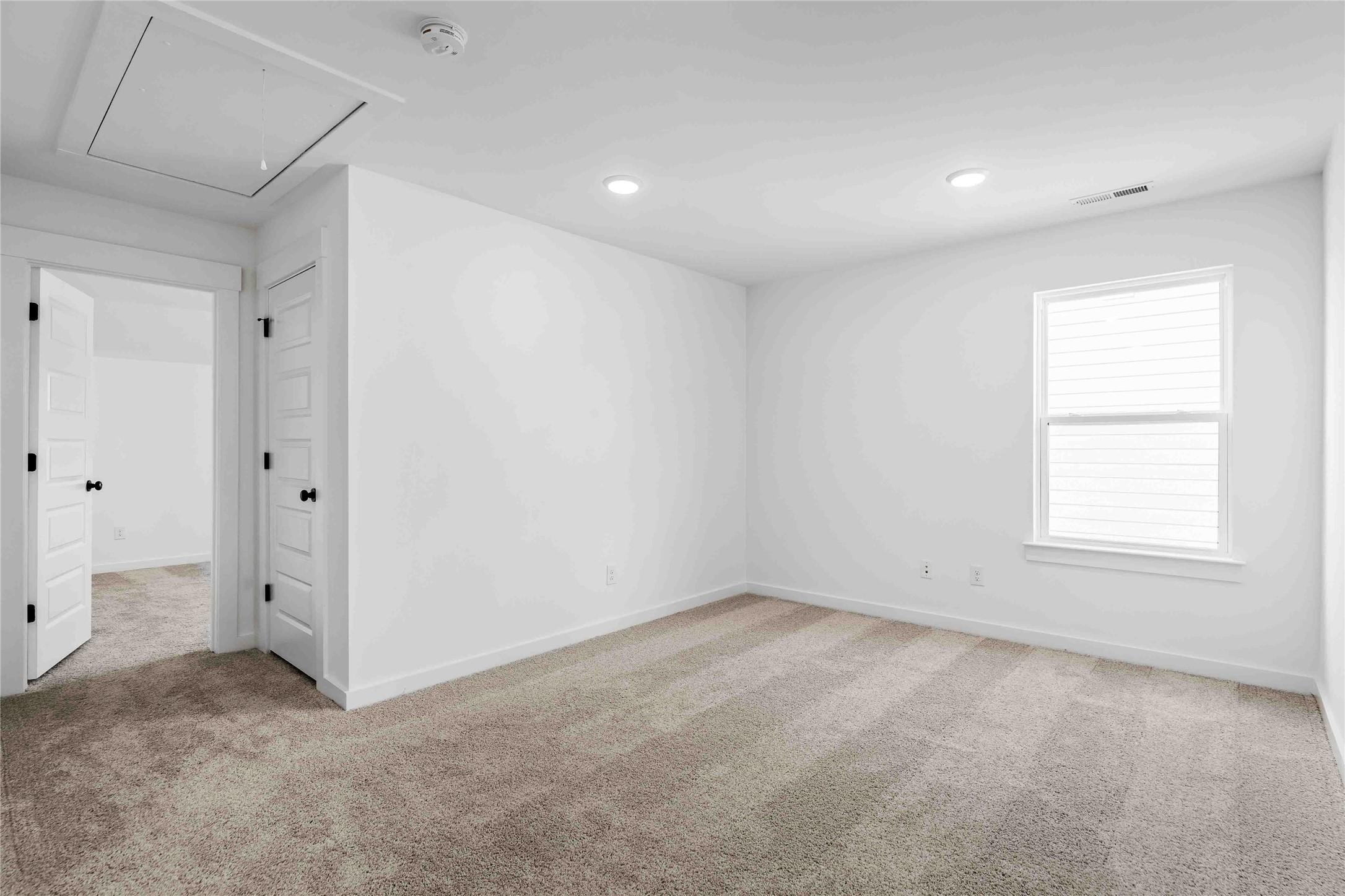 Bright, carpeted secondary bedroom with white walls in The Ash O floor plan by Davidson Homes in Heartland, Texas.