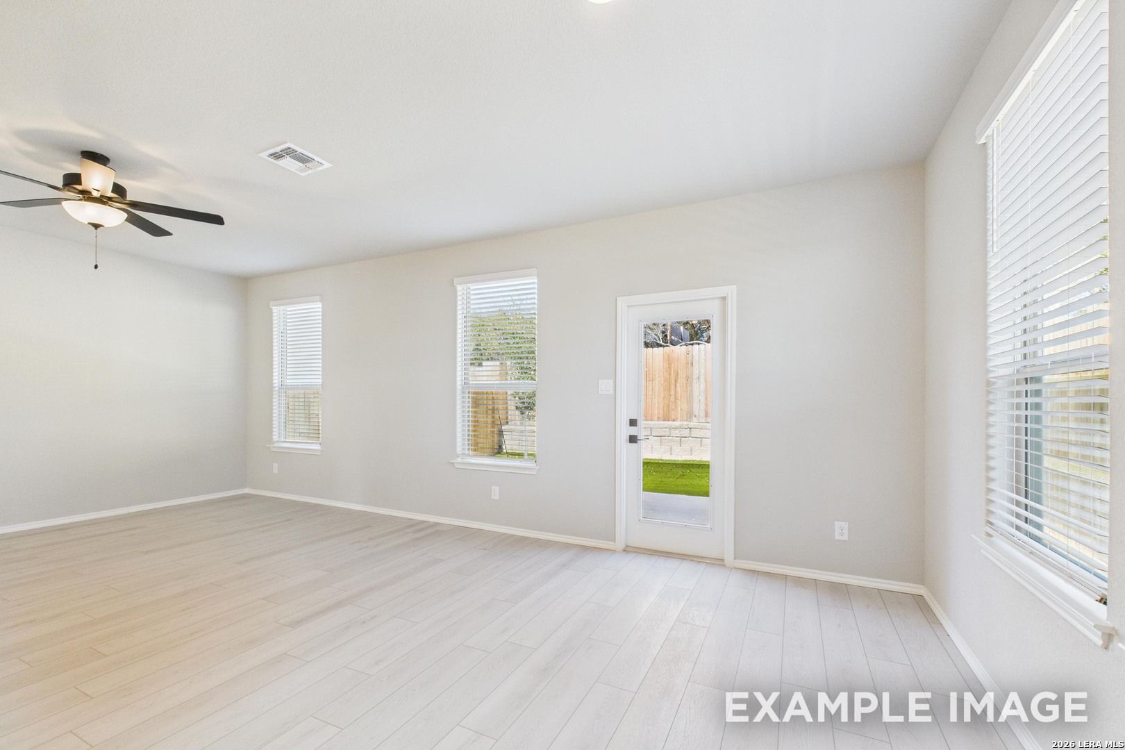 Bright living room with light wood floors and ceiling fan in The Charlotte B floor plan at Cedar Heights, San Antonio.