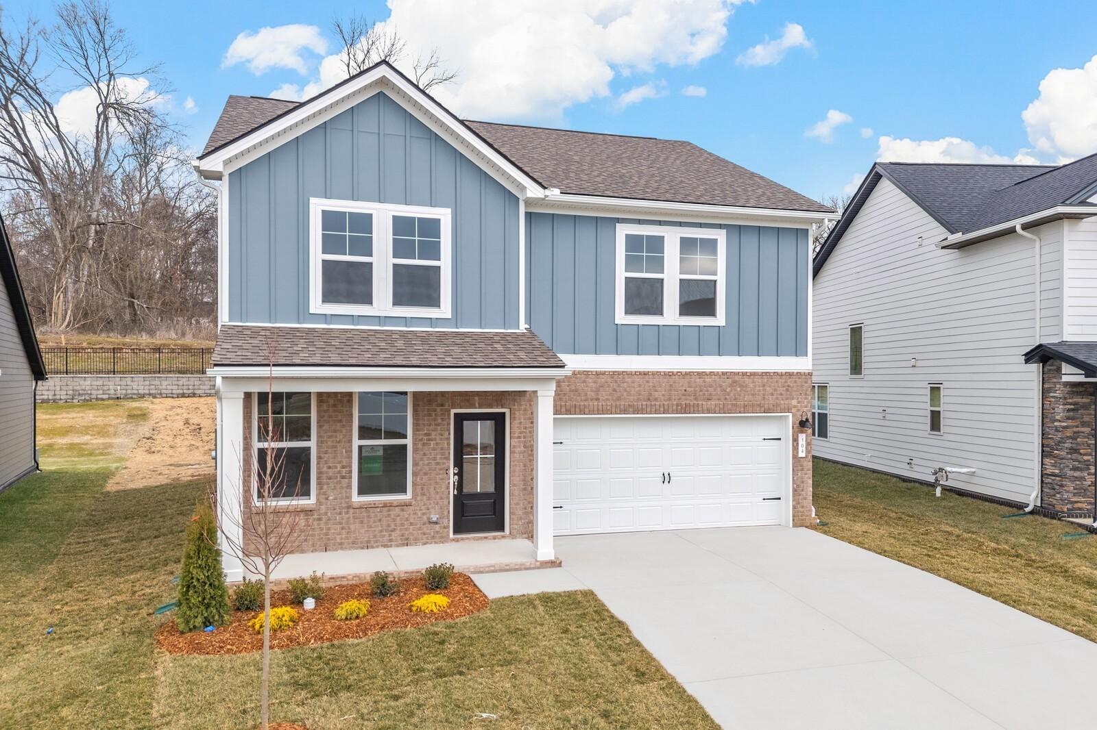 Modern two-story blue home with brick accents, two-car garage, and landscaped front yard in Woods Crossing, Gallatin, Tennessee - Davidson Homes The Logan C