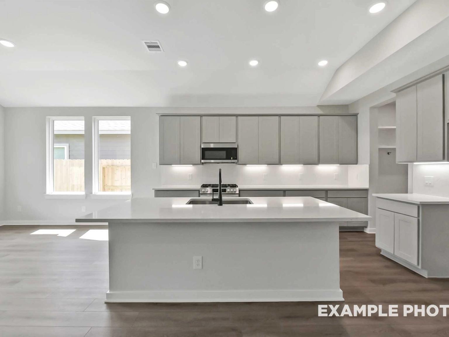 Modern kitchen with white quartz island and grey cabinetry in The Sequoia C floor plan at Sundance Cove, Crosby, Texas.