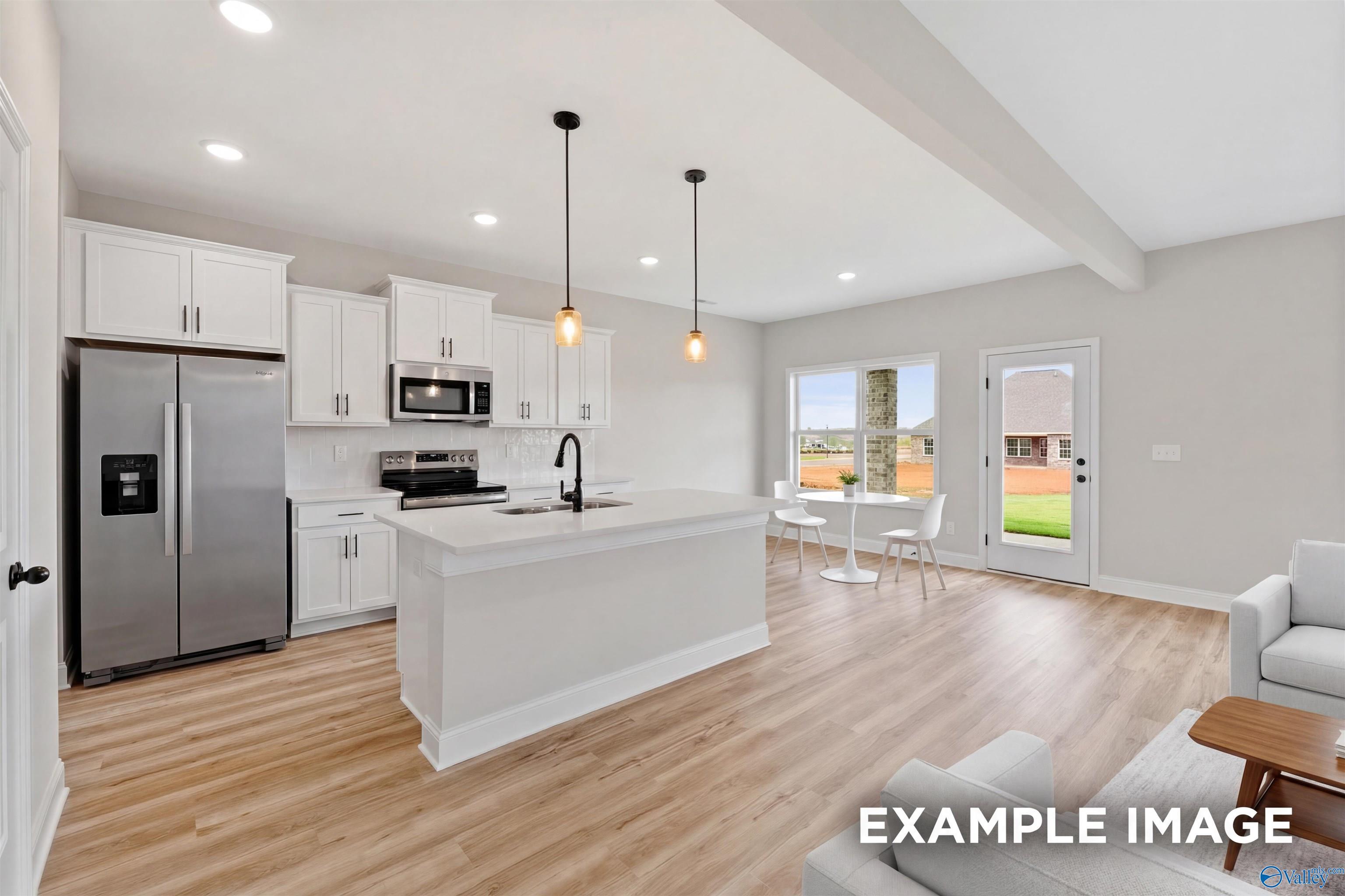 Modern kitchen with white cabinets, island, and stainless steel appliances in The Shelby B floor plan, Jaguar Hills, AL.