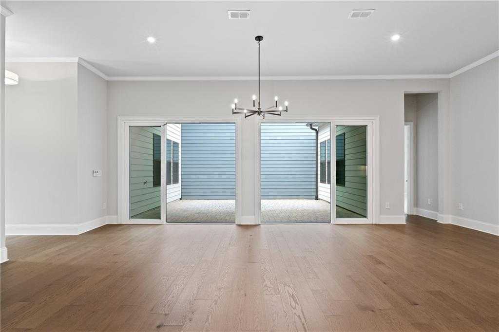 Expansive great room with hardwood floors, chandelier, and open French doors to covered patio in Davidson Homes Seaside B, Woodstock, GA