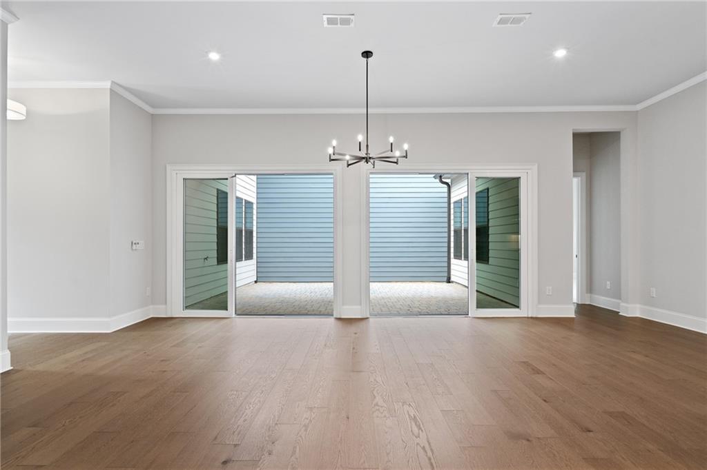 Expansive great room with hardwood floors, chandelier, and open French doors to covered patio in Davidson Homes Seaside B, Woodstock, GA
