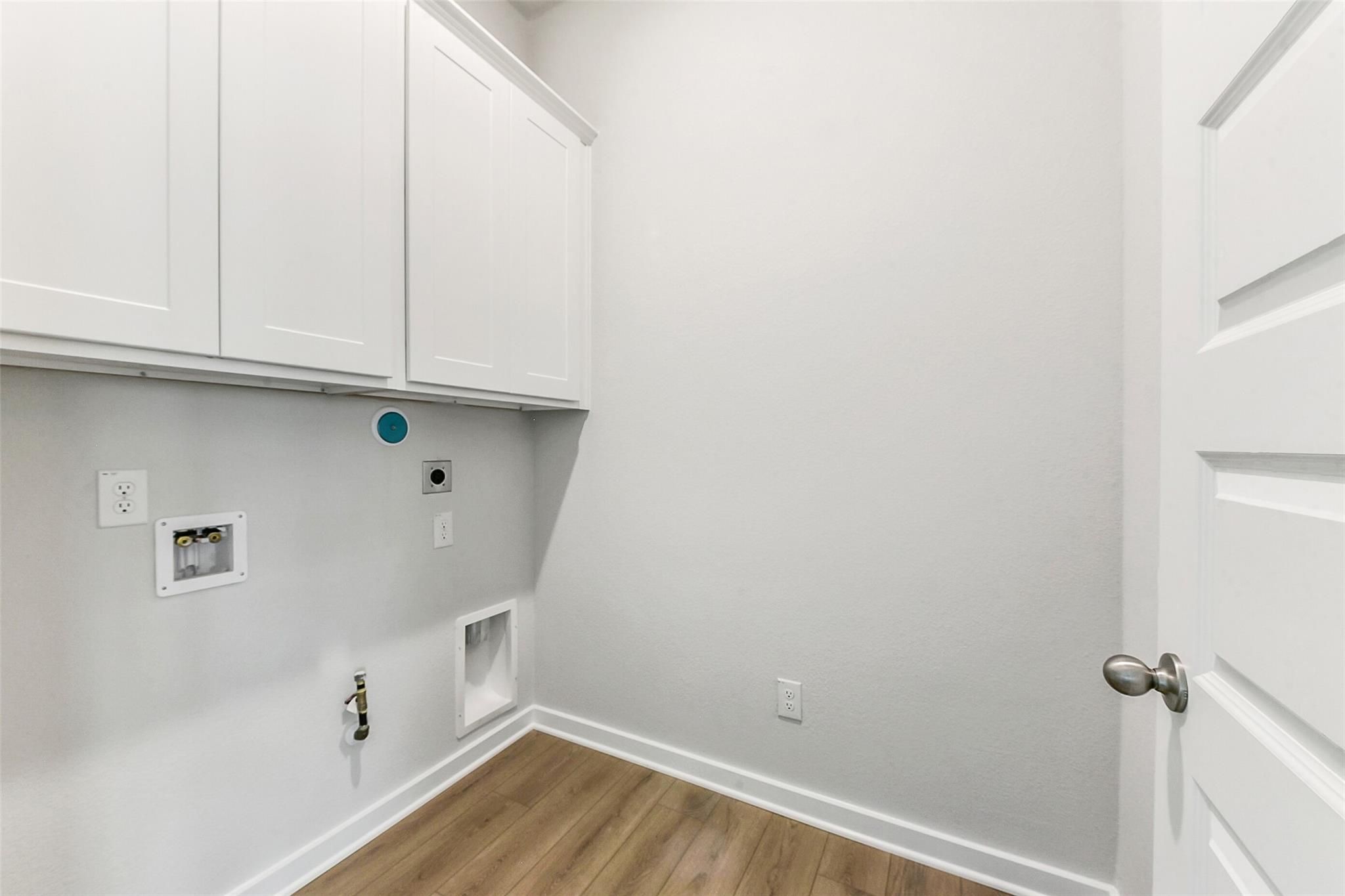Modern laundry room with white shaker cabinets, washer/dryer hookups, utility sink in Davidson Homes The Costa B, Dayton, Texas