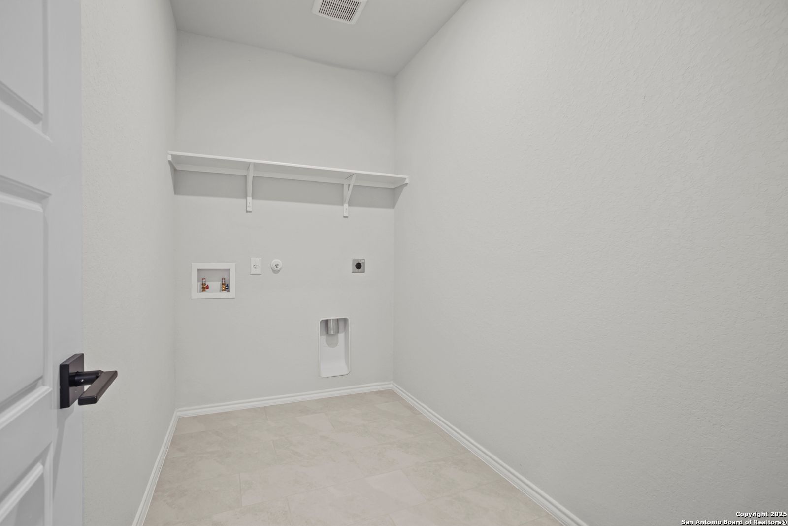 Modern laundry room with built-in white shelves, washer dryer hookups in Davidson Homes The Douglas C, Seguin, Texas