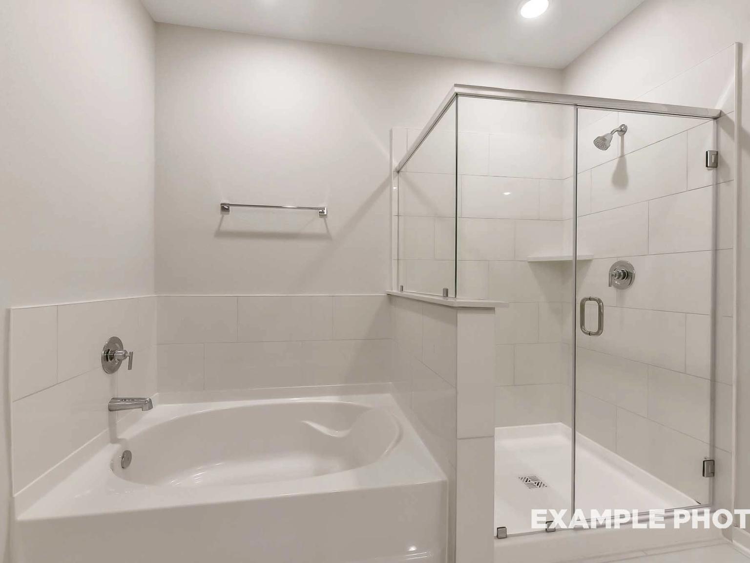 Modern primary bathroom with soaking tub and separate glass-enclosed shower in The Brookside F, Enclave at Newport, Crosby.