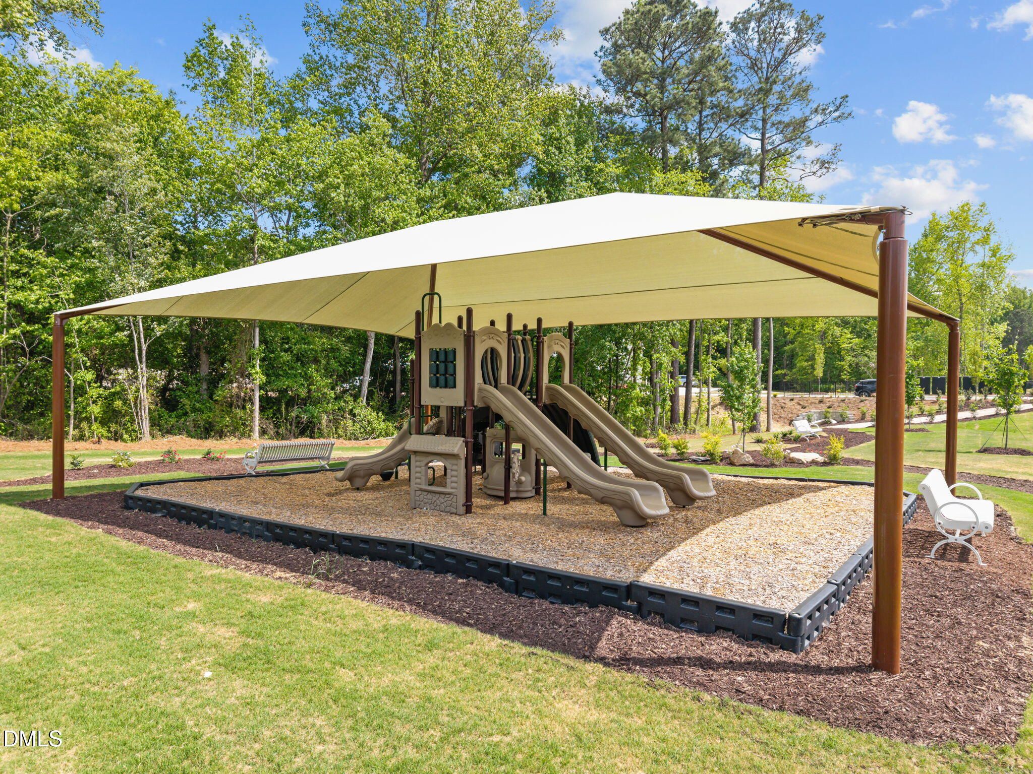 Shaded playground with playset, dual slides, and benches in lush trees at Wendell Ridge, Wendell, North Carolina