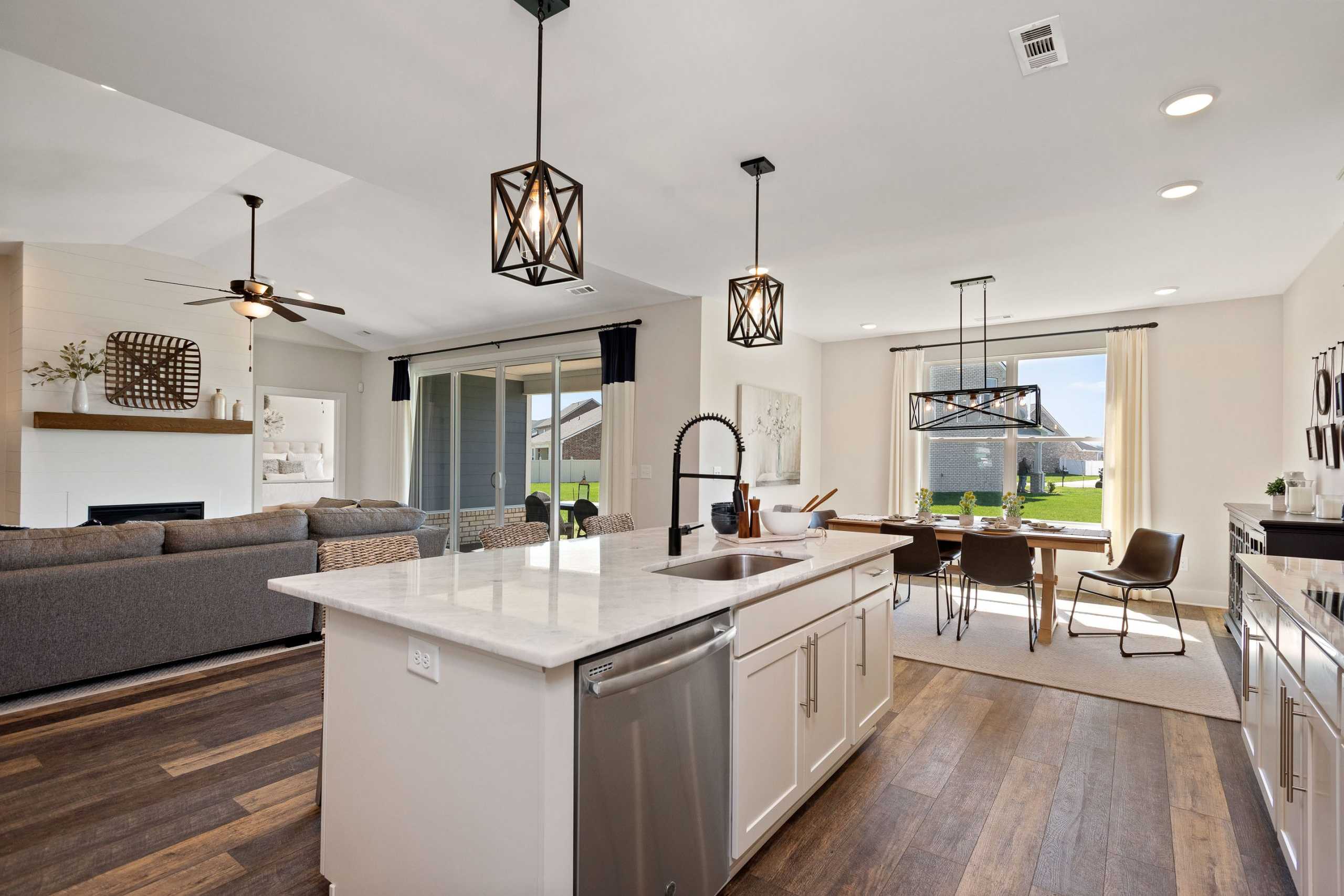 Open-concept kitchen and living area at Rivers Edge in Murfreesboro TN with white island, hardwood floors, pendant lights, and backyard view