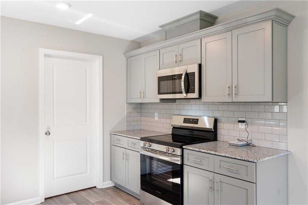 Modern kitchen with gray shaker cabinets, granite countertops, stainless steel appliances in Davidson Homes The Washington, Phenix City AL