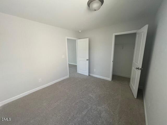 Bright bedroom with gray carpet, white walls, open walk-in closet and bath door in Davidson Homes The Adalynn A, Lillington, NC