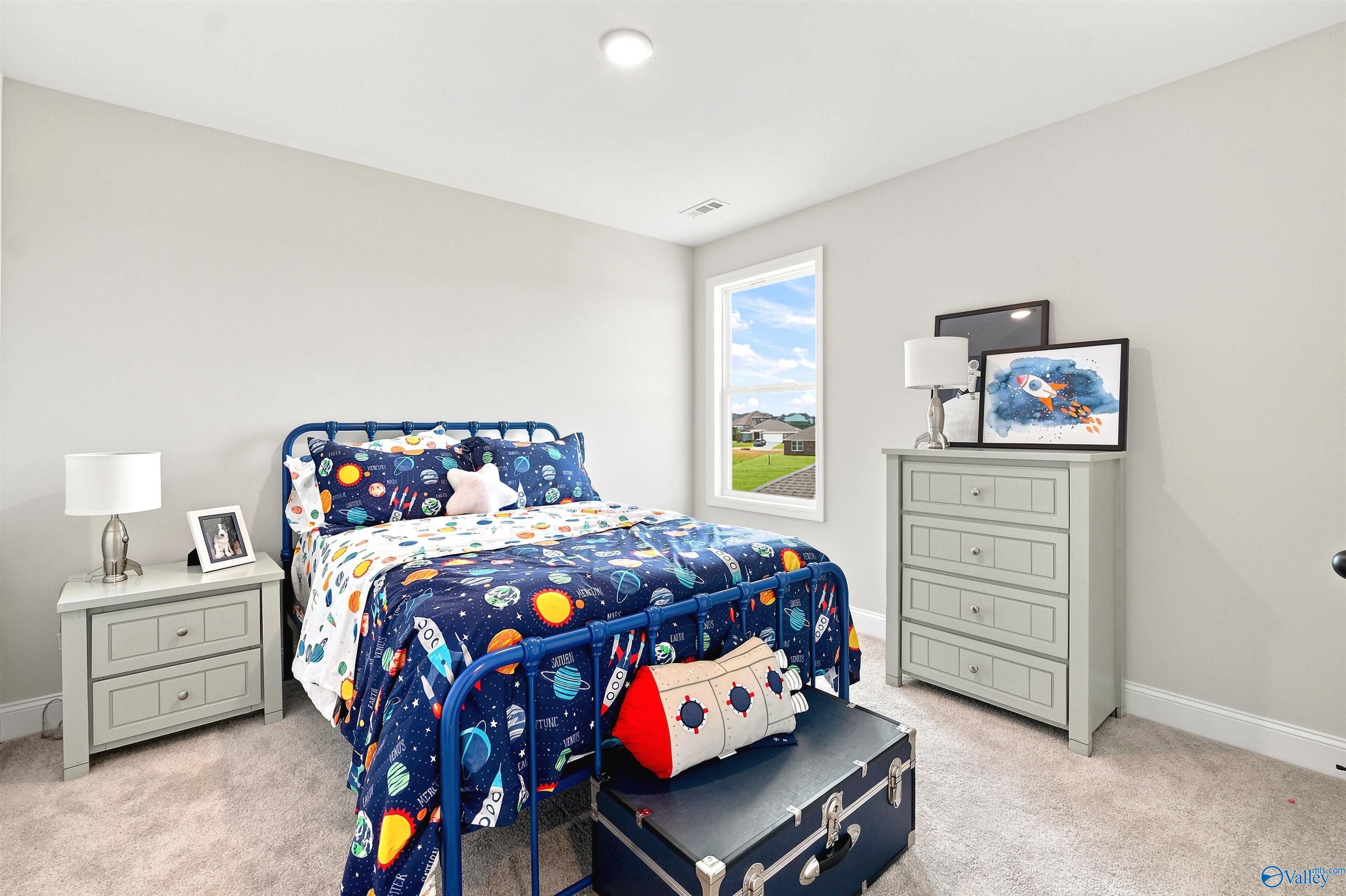 Spacious kid's bedroom with space-themed bedding in The Burton B floor plan at Heritage Lakes, New Market, Alabama.