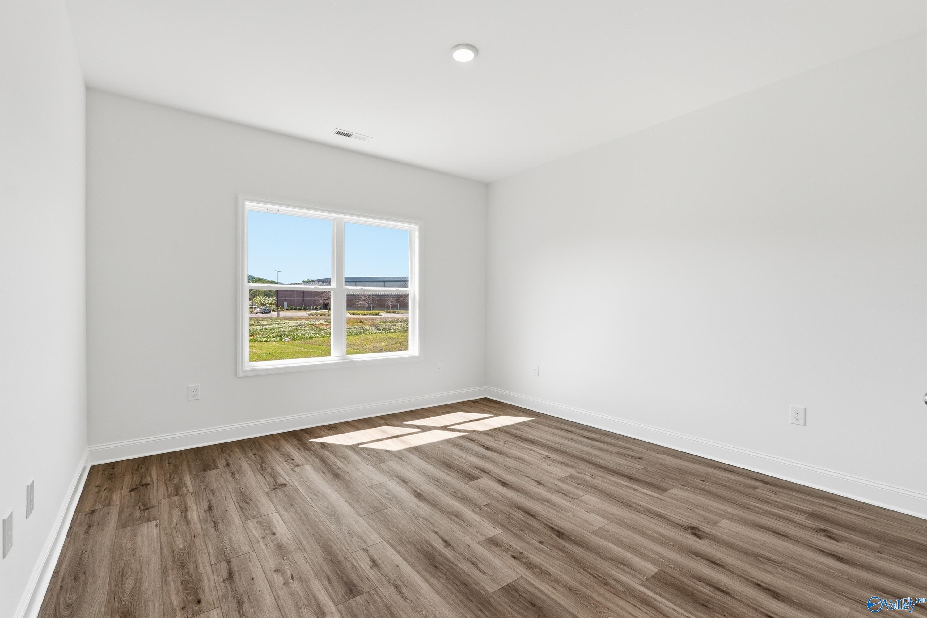 Bright, spacious bedroom with wood-look flooring in The Asheville floor plan by Davidson Homes in Jaguar Hills, Huntsville.