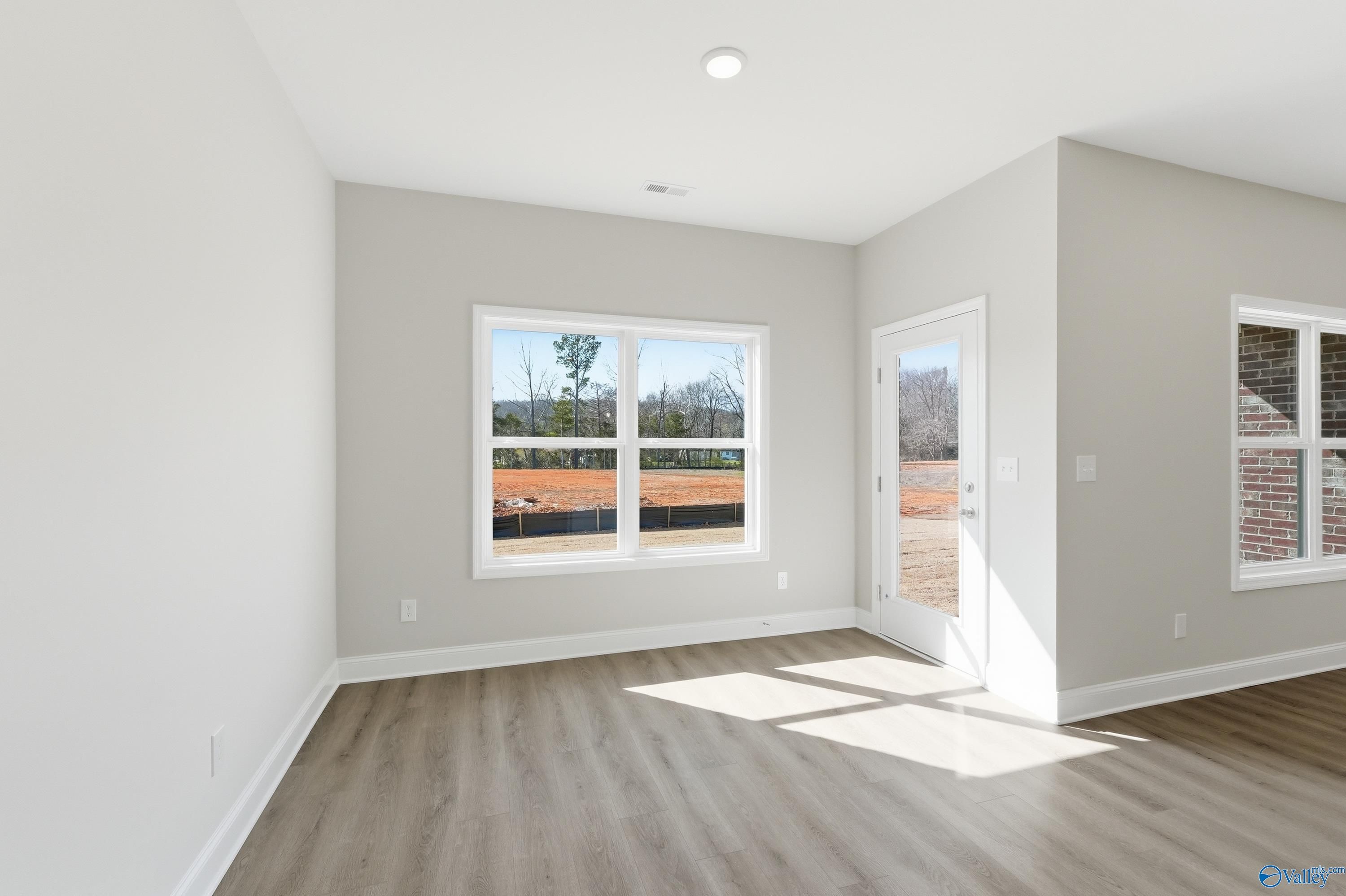 Bright living room with gray walls, large windows, glass patio door, and hardwood floors in The Asheville C, Huntsville AL