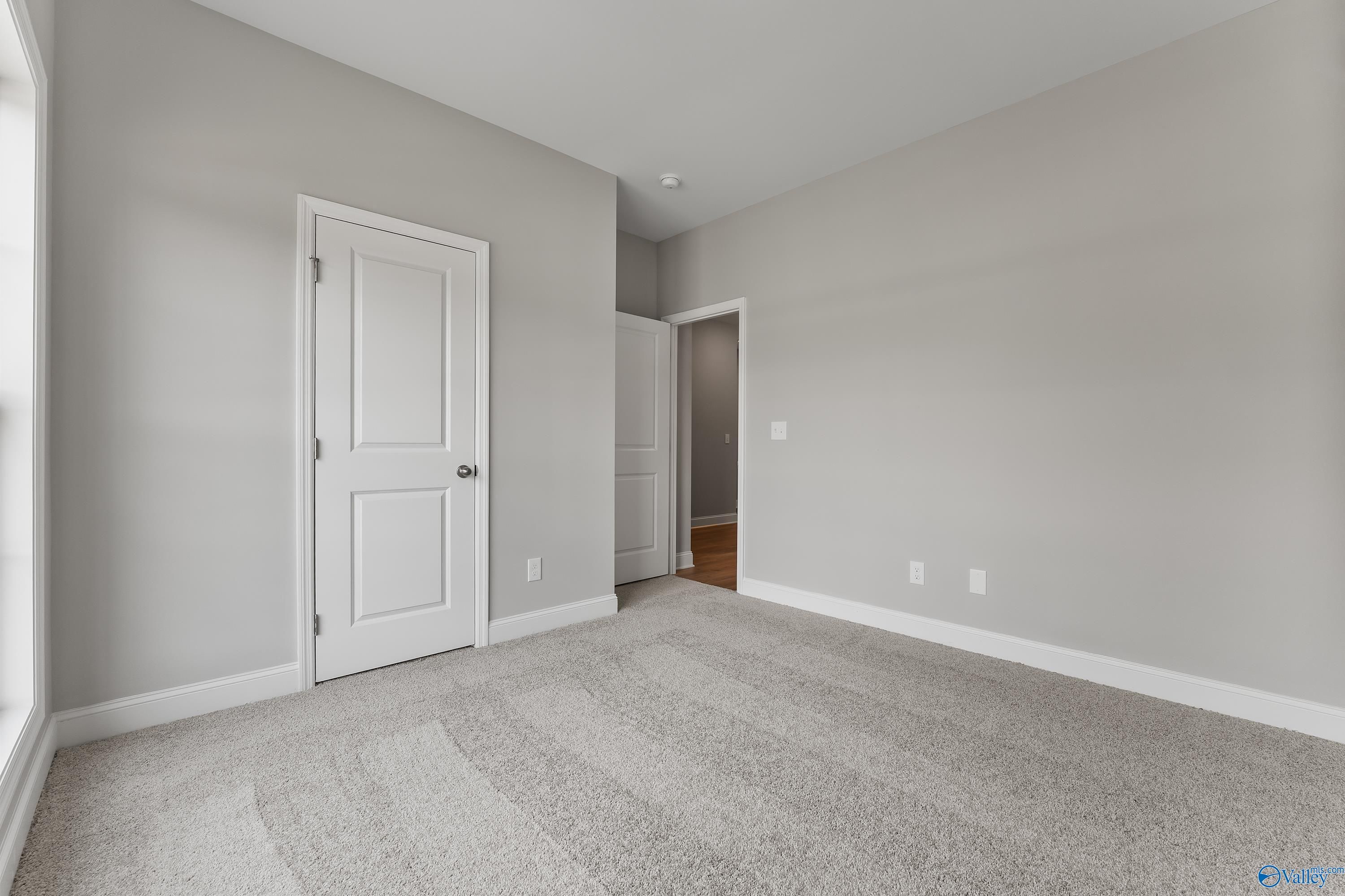 Spacious secondary bedroom with gray walls, white doors, and carpet flooring in Davidson Homes The Franklin, Huntsville, AL
