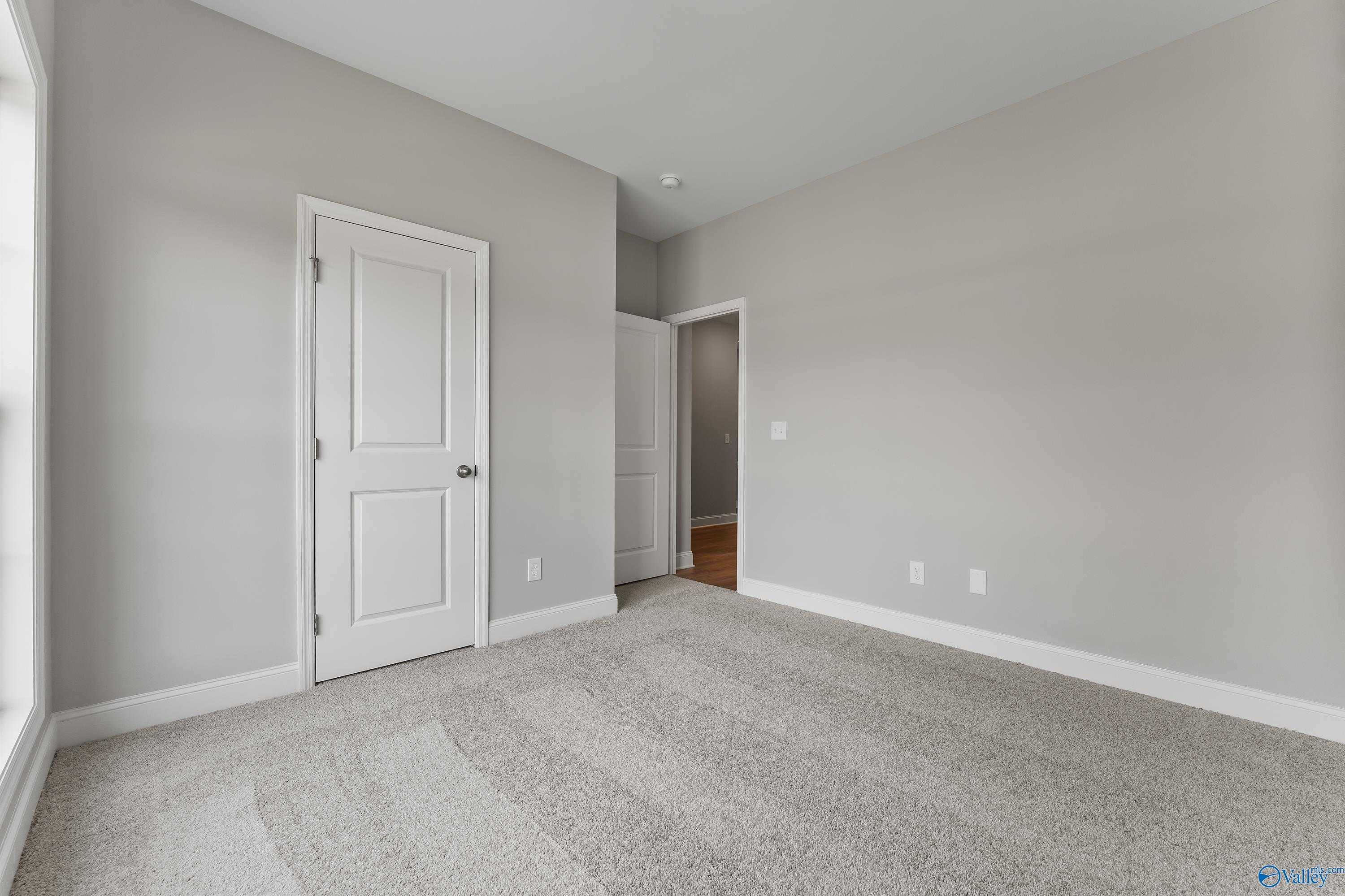 Spacious secondary bedroom with gray walls, white doors, and carpet flooring in Davidson Homes The Franklin, Huntsville, AL
