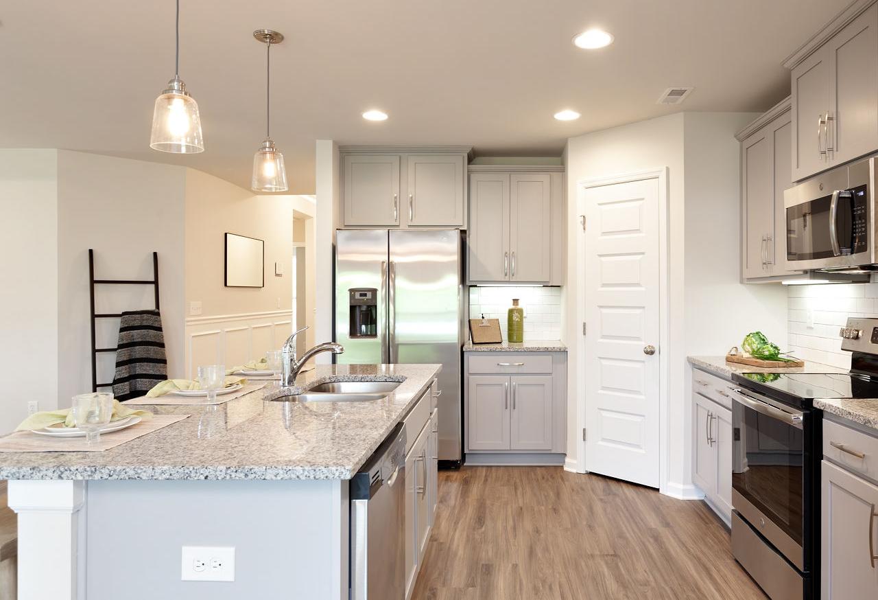 Spacious kitchen in The Franklin by Davidson Homes featuring gray cabinets, stainless steel appliances, granite island, and hardwood floors