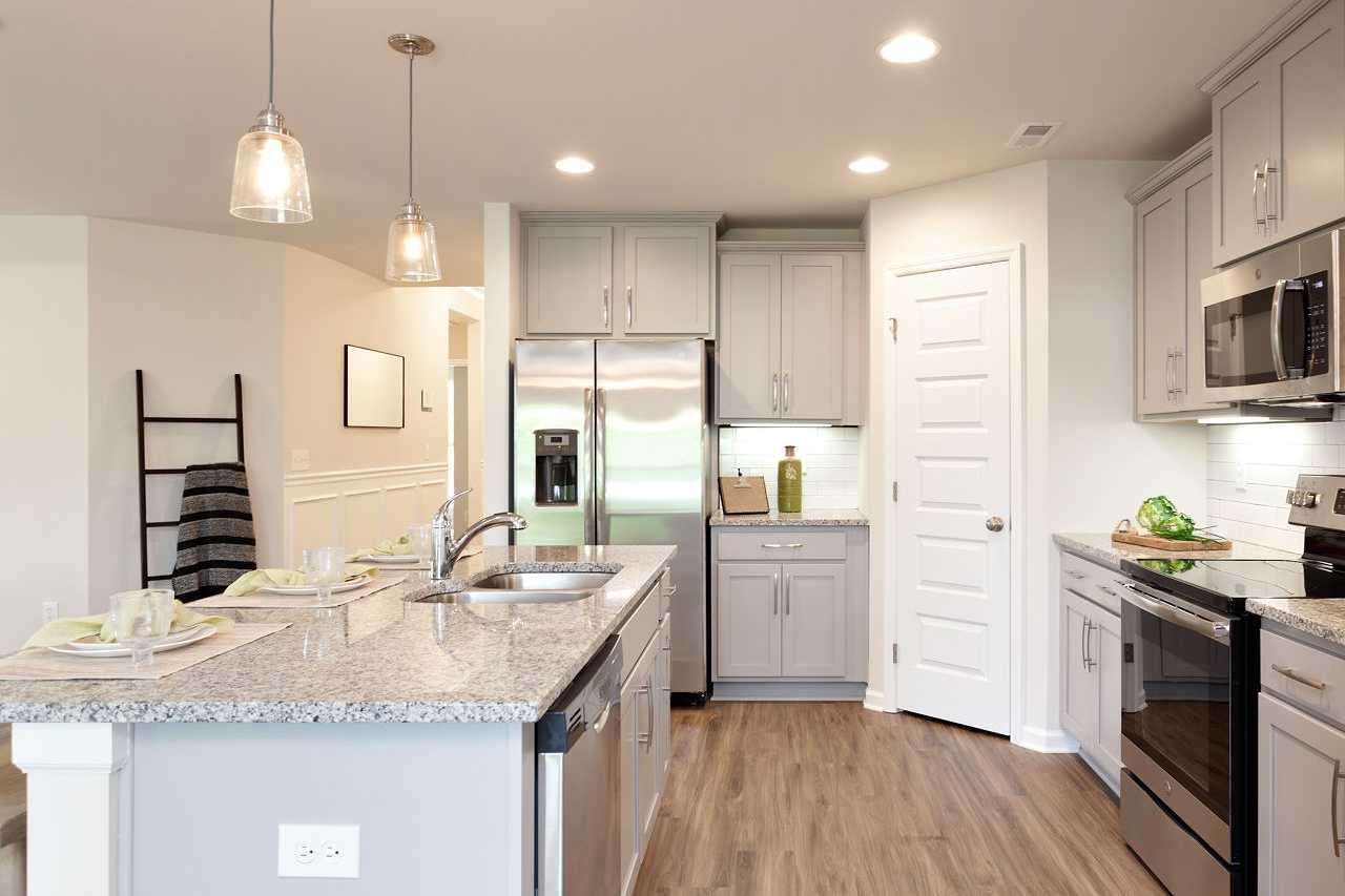 Spacious kitchen in The Franklin by Davidson Homes featuring gray cabinets, stainless steel appliances, granite island, and hardwood floors