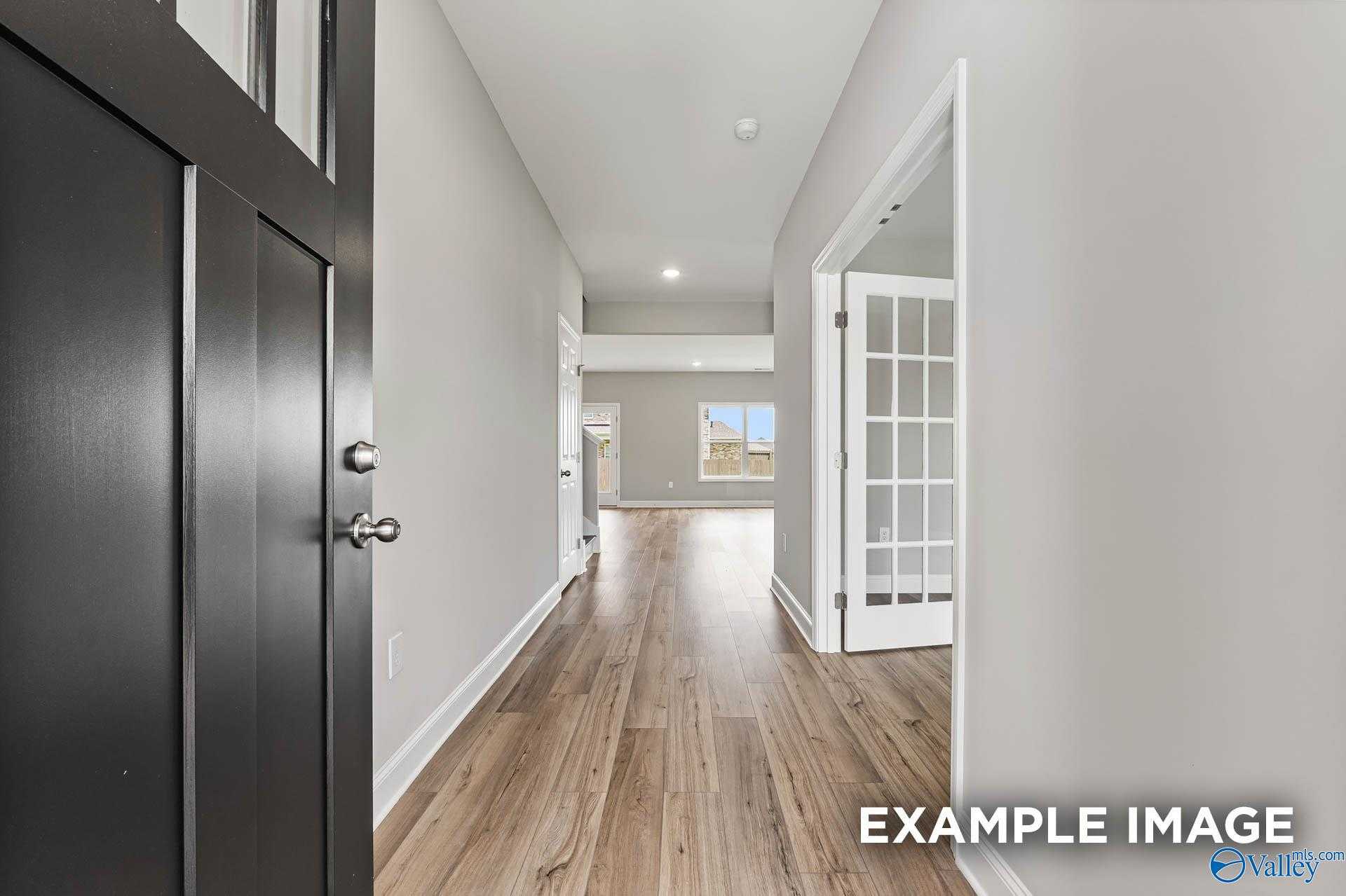 Spacious entry hallway with light hardwood floors, gray walls, and French doors in Davidson Homes The Chelsea A, Athens, Alabama