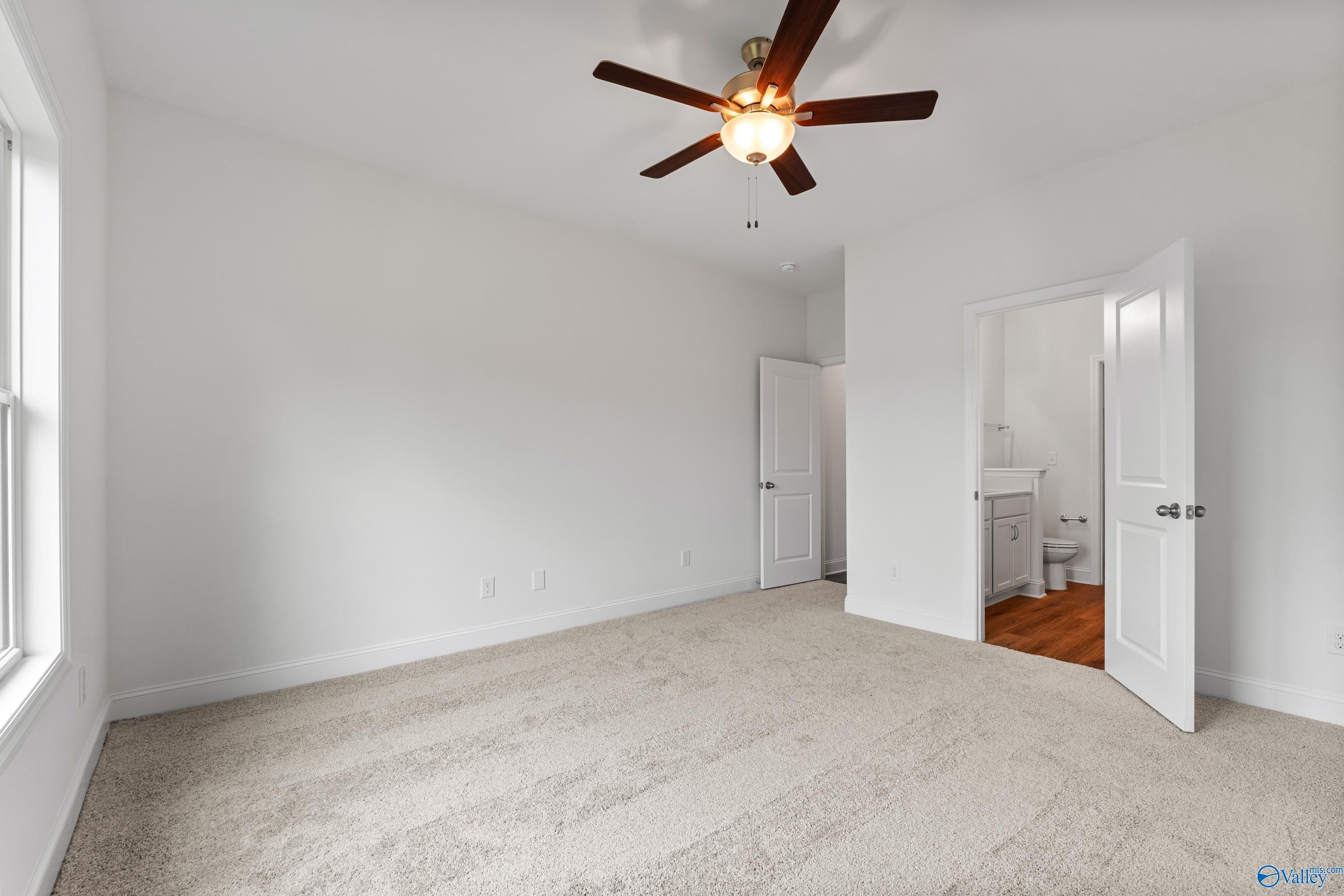 Bright bedroom with ceiling fan, beige carpet, and attached bath visible through open door in Davidson Homes The Asheville C, New Market, AL