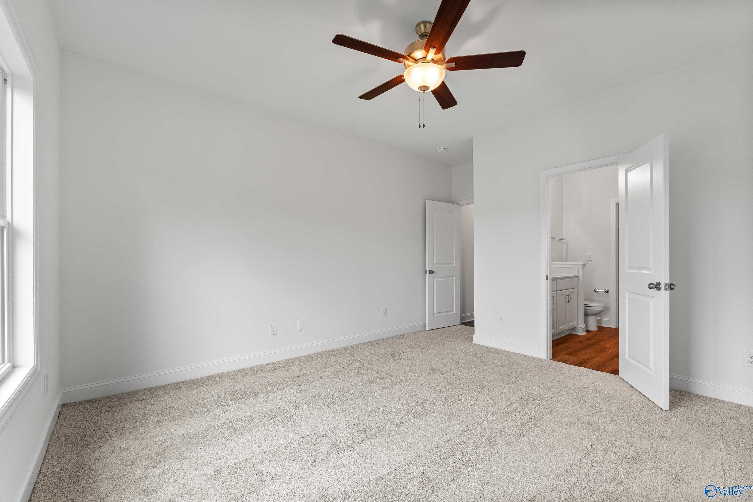 Bright bedroom with ceiling fan, beige carpet, and attached bath visible through open door in Davidson Homes The Asheville C, New Market, AL