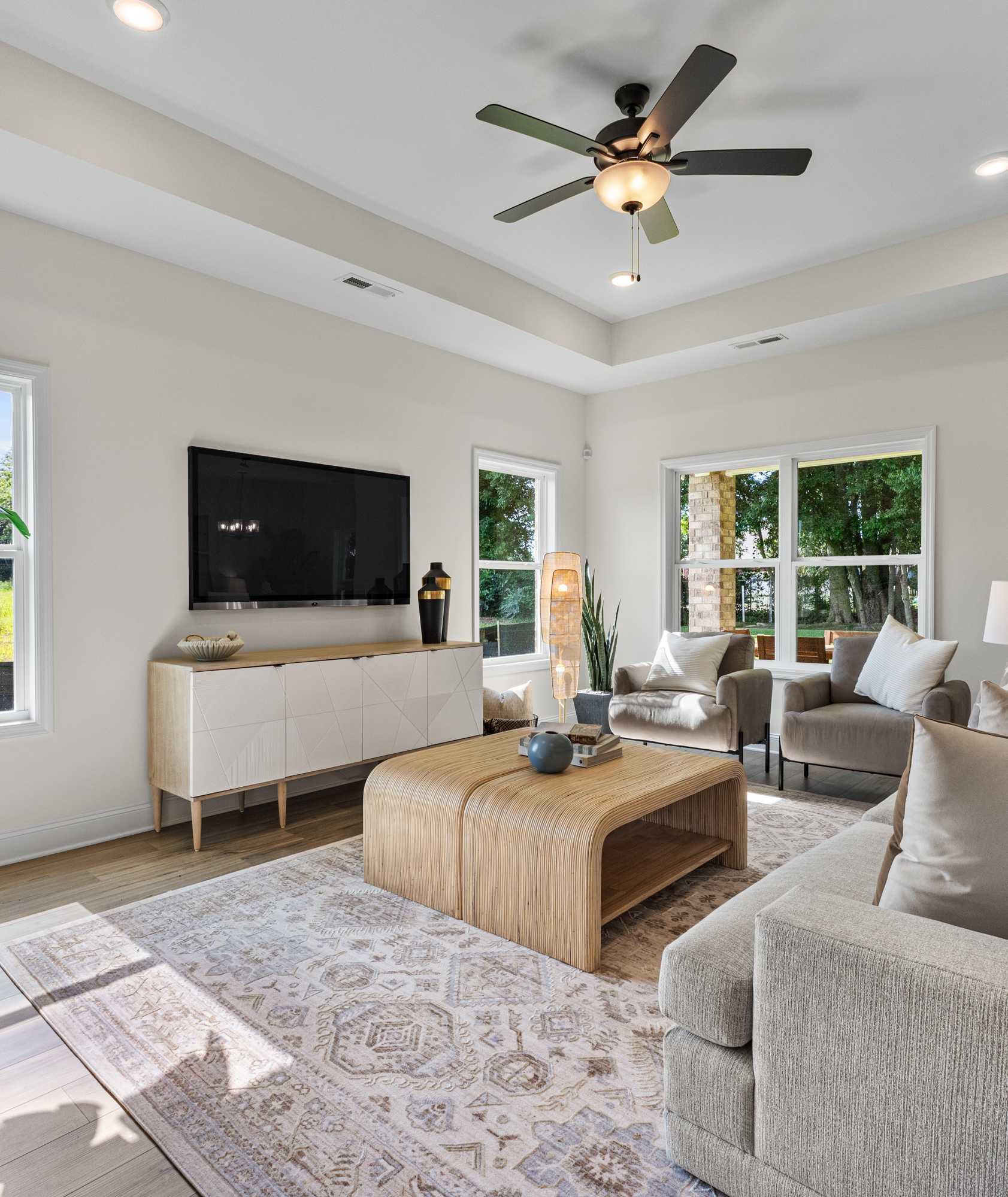 Spacious living room at Little Creek in Arab Alabama with large windows, beige sofa, ceiling fan, tropical plants
