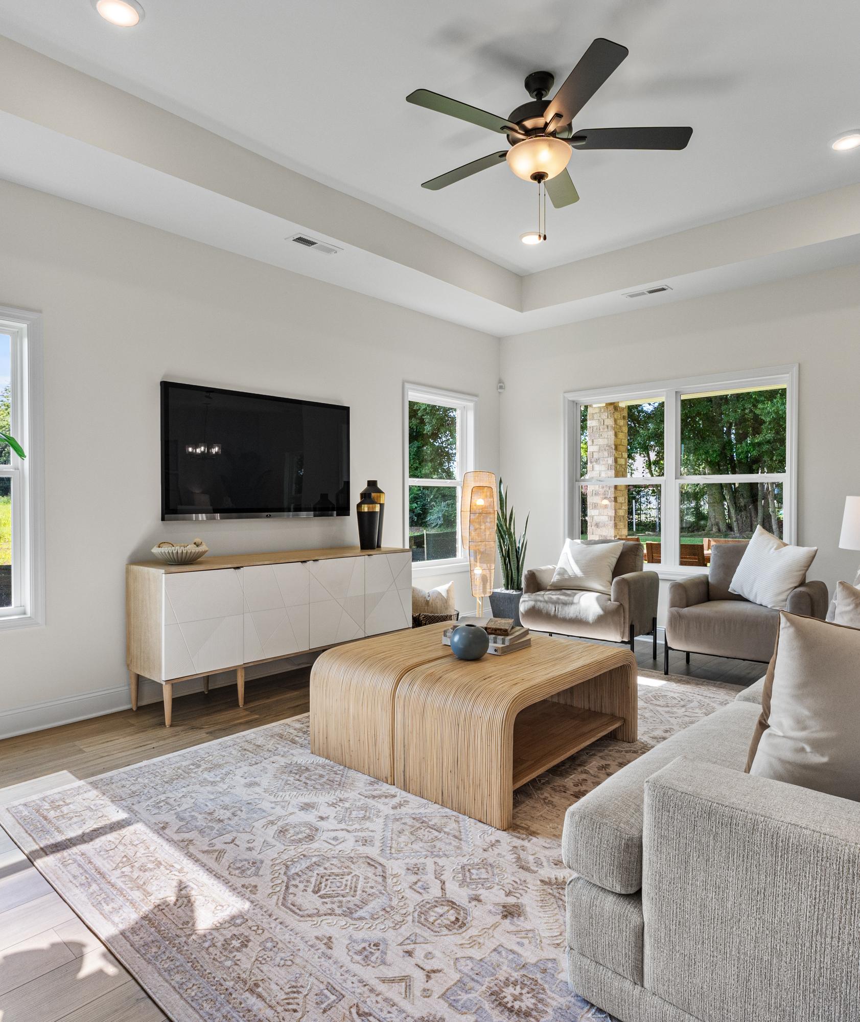 Spacious living room at Little Creek in Arab Alabama with large windows, beige sofa, ceiling fan, tropical plants