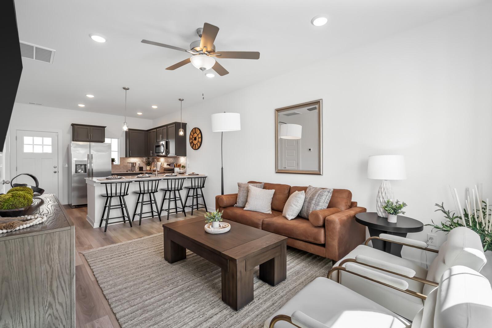 Open-concept living room and kitchen at The Towns at Red River in Gallatin, TN with leather sofa, bar island, and modern lighting