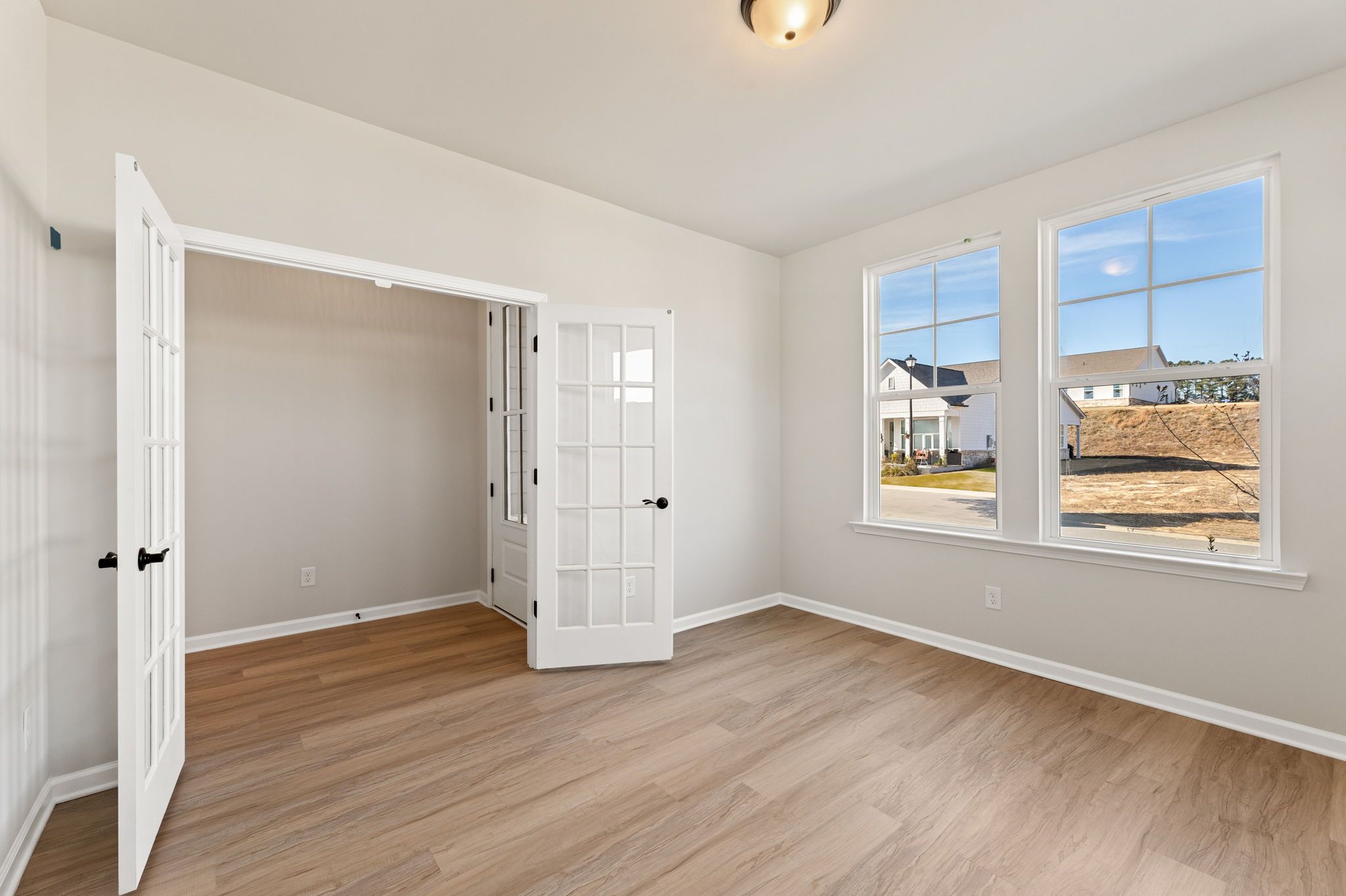 Bright study with open French doors, hardwood floors, and large windows overlooking neighborhood in Davidson Homes The Glenwood C, Loganville, GA