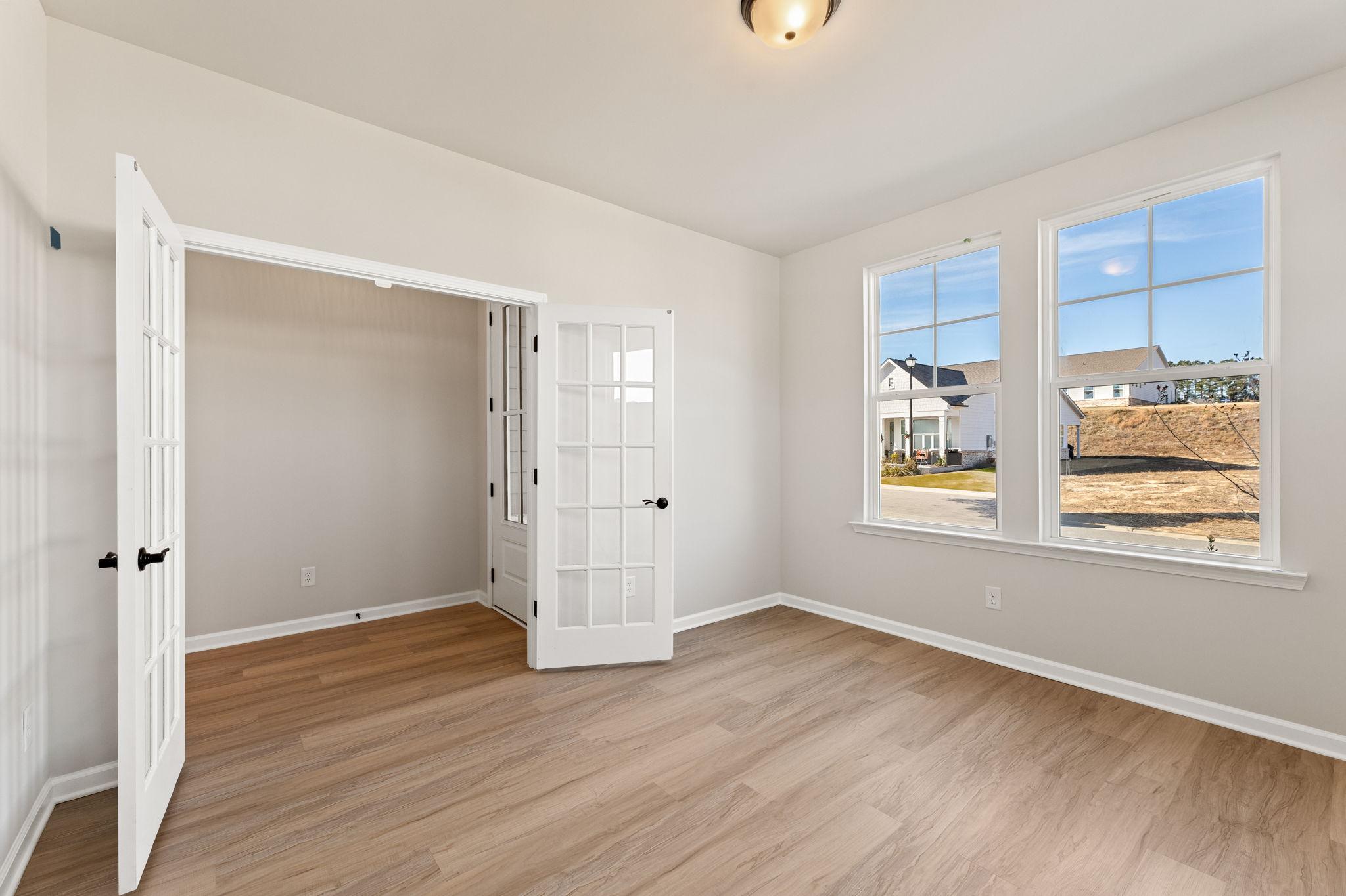 Bright study with open French doors, hardwood floors, and large windows overlooking neighborhood in Davidson Homes The Glenwood C, Loganville, GA