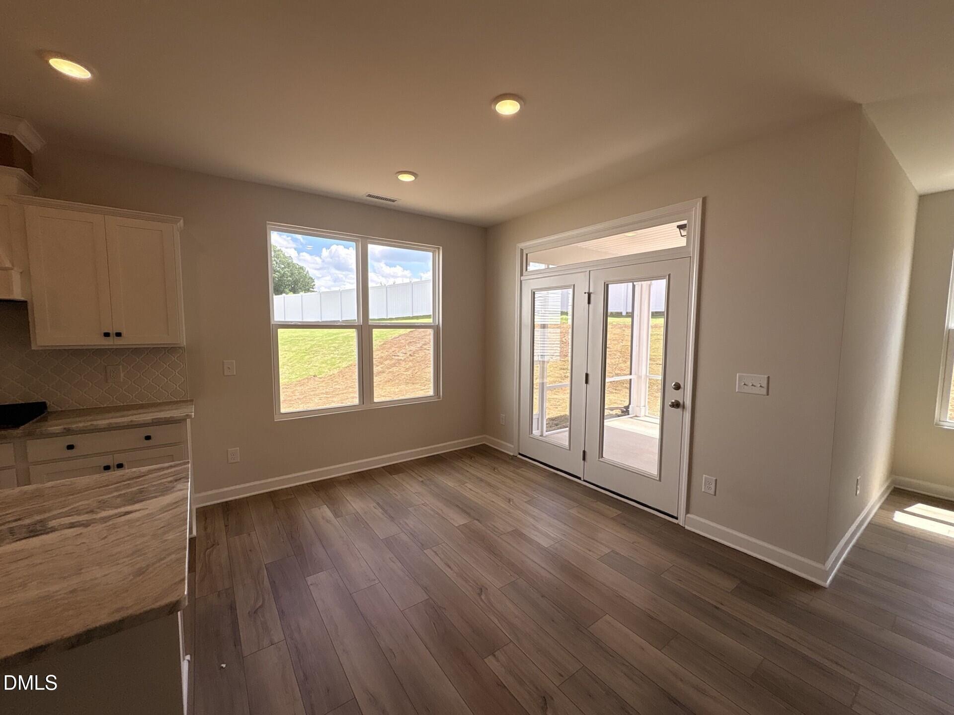 Bright dining area with wood-look flooring and glass doors to patio in The Ash C floor plan at Woodland Crossing, Zebulon.