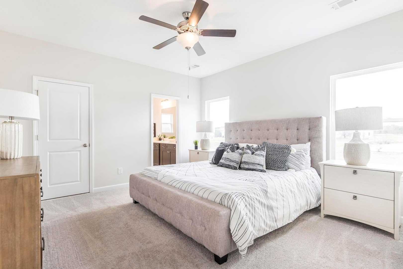 Spacious master bedroom at Cape Reserve Donahue Ridge Auburn Alabama with king bed gray upholstered headboard nightstands ceiling fan and en-suite bath