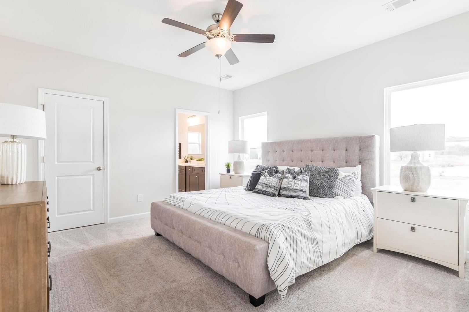 Spacious master bedroom at Cape Reserve Donahue Ridge Auburn Alabama with king bed gray upholstered headboard nightstands ceiling fan and en-suite bath