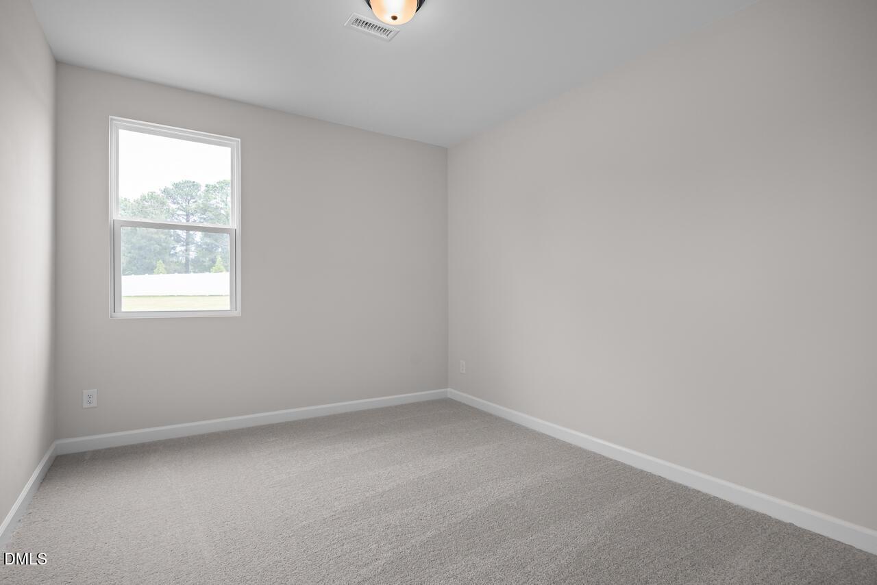 Bright, carpeted bedroom with neutral walls in The Willow B floor plan by Davidson Homes in Woodland Crossing, Zebulon, NC.