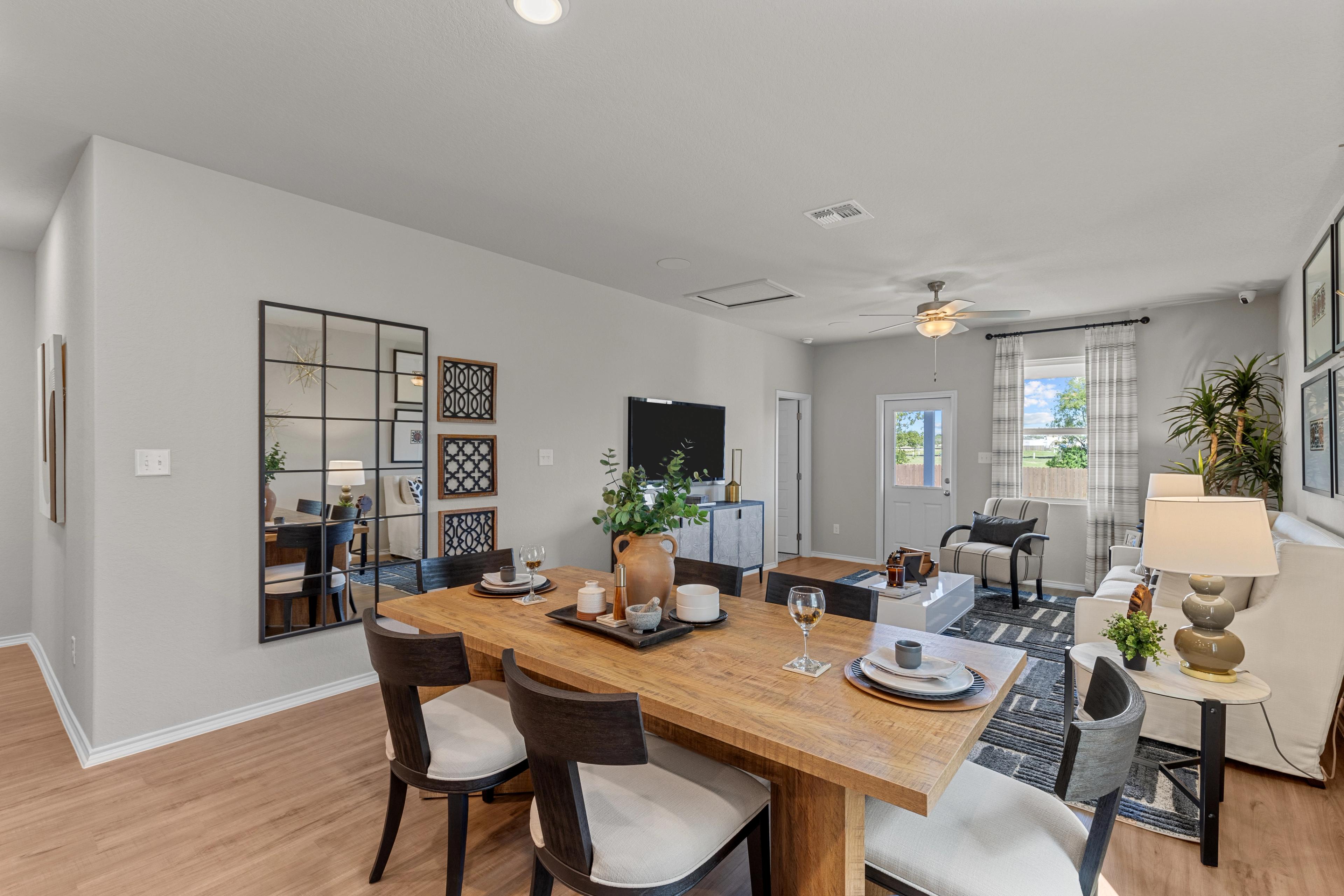 Spacious dining area in The Sabine B home with wooden table, upholstered chairs, wall mirrors, and potted plants