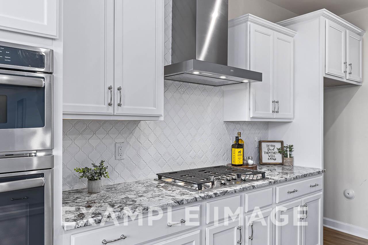 Modern white kitchen in The Willow C featuring shaker cabinets, stainless steel double oven, gas cooktop, subway tile backsplash, and quartz island