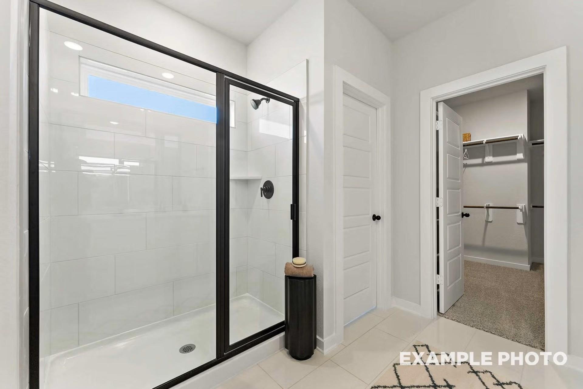 Modern master bathroom with glass-enclosed walk-in shower, subway tiles, and adjacent closet in Davidson Homes The Everett C, Dayton, Texas